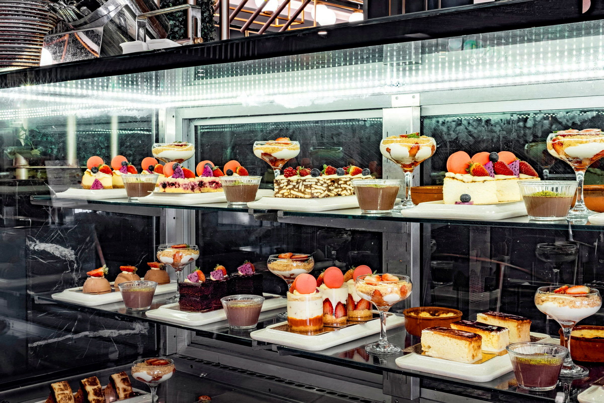 En glasmonter fylld med olika desserter och bakverk. (AI-genererad text)
