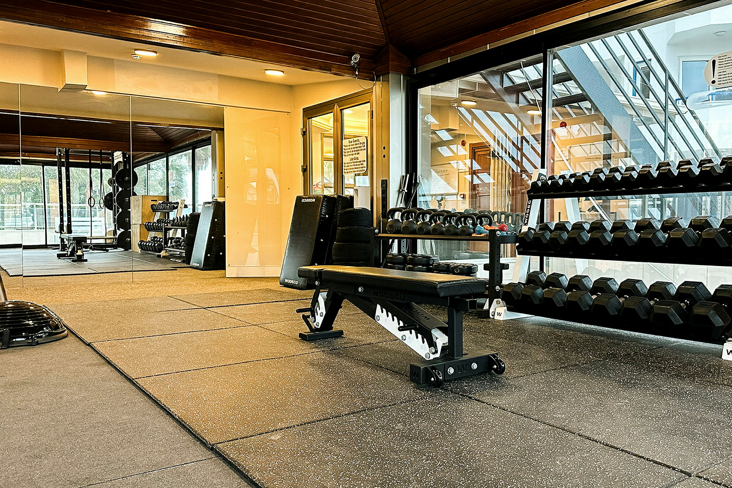 Interiör av ett gym med träningsutrustning, vikter och en träningsbänk. (AI-genererad text)