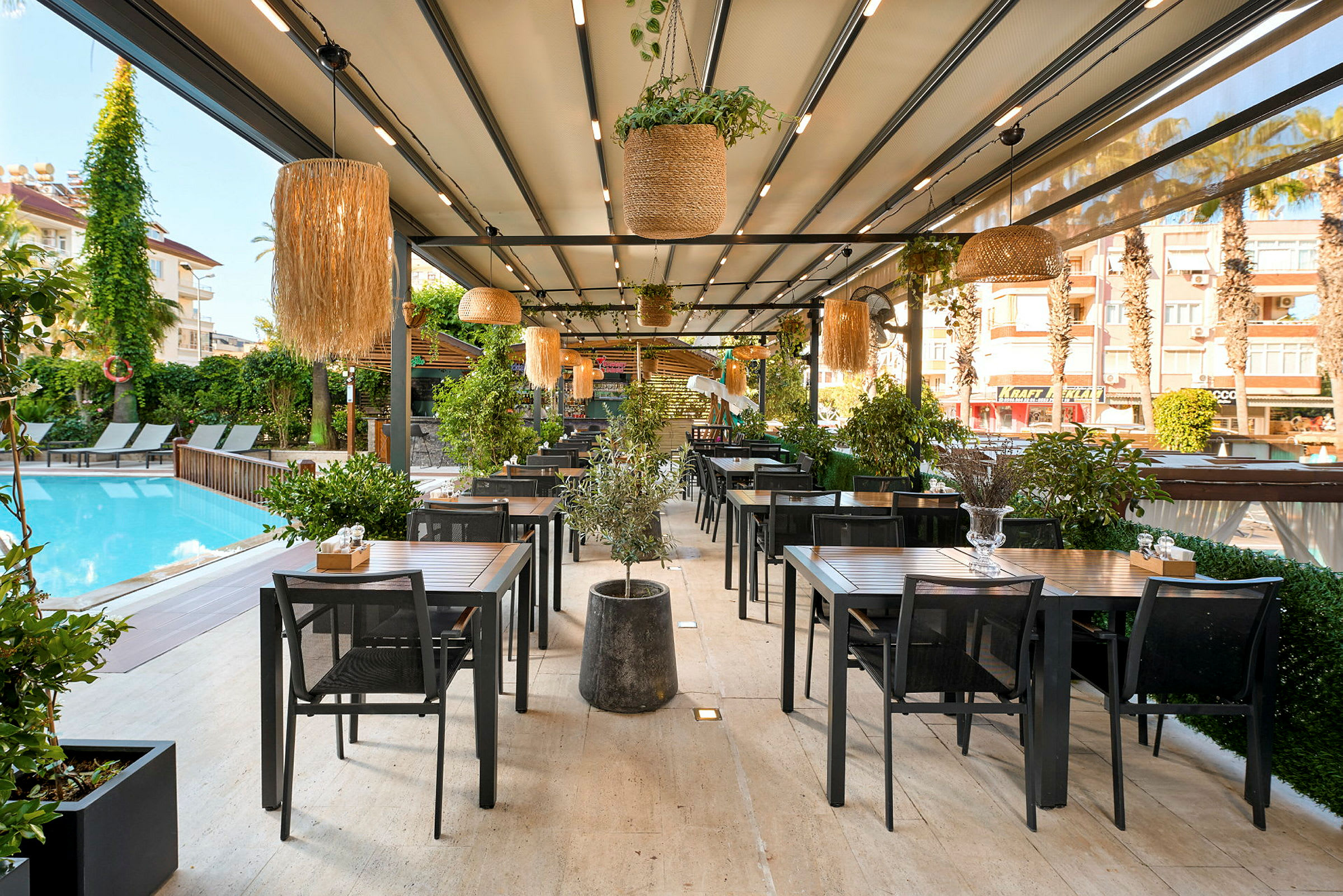 Utomhusrestaurang vid en pool med bord och stolar samt gröna växter. (AI-genererad text)