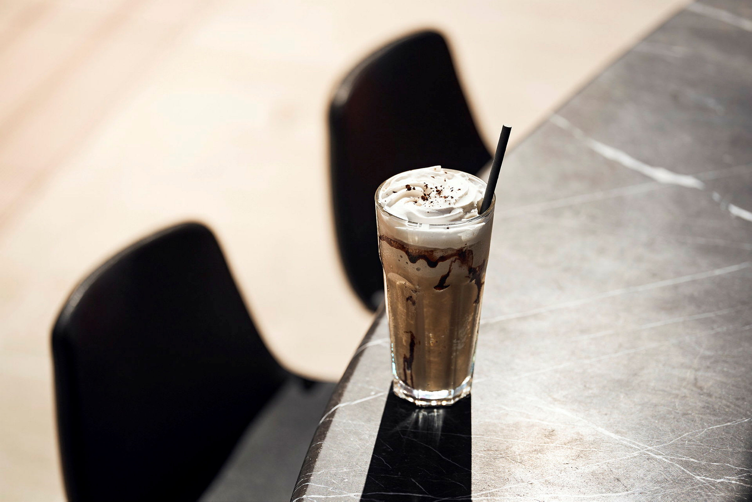 Ett glas iskaffe med grädde och choklad dekorerar ett bord. (AI-genererad text)