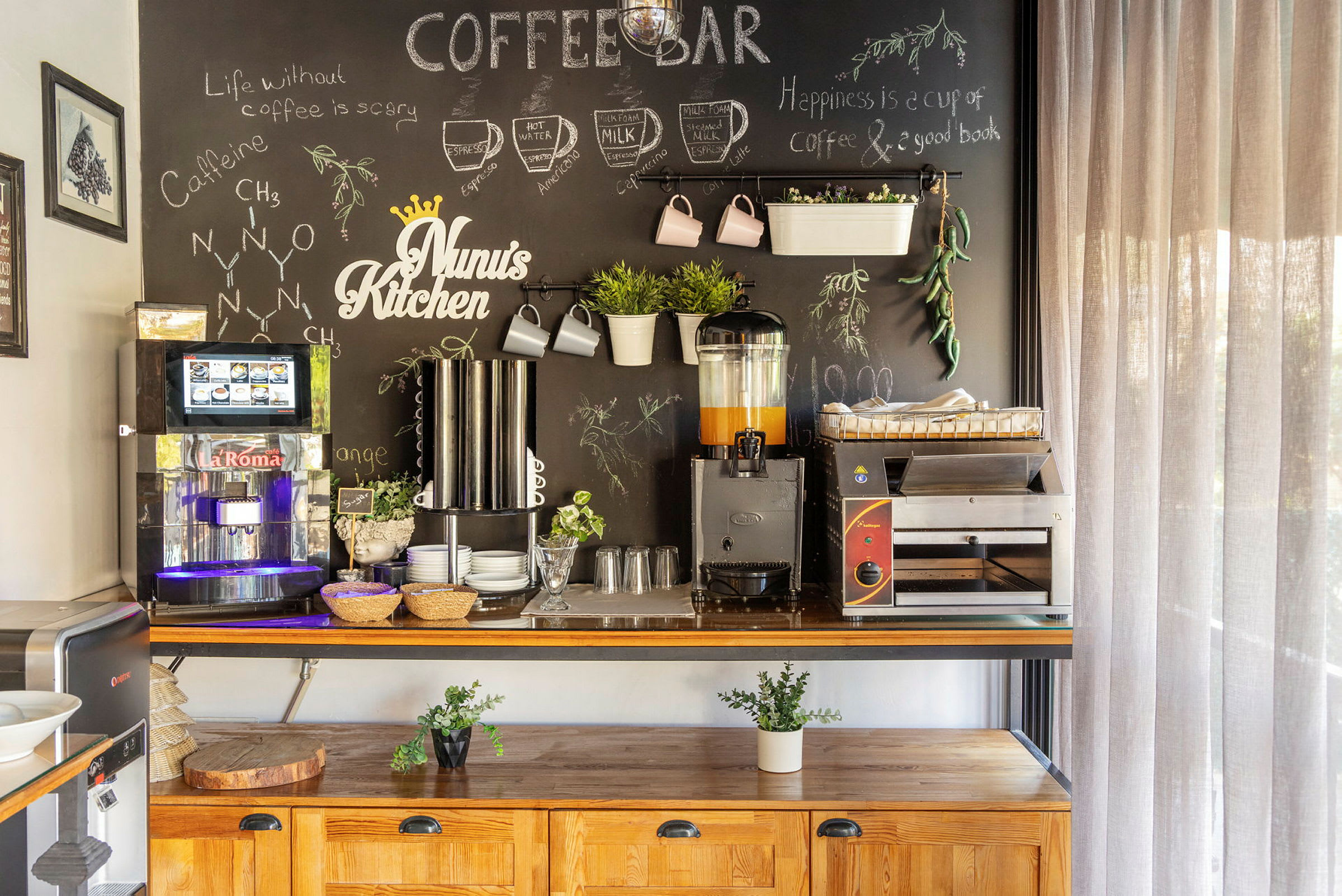 En kaffehörna med en svart tavla fylld med teckningar och text, en kaffemaskin, koppar och en juicebehållare. (AI-genererad text)