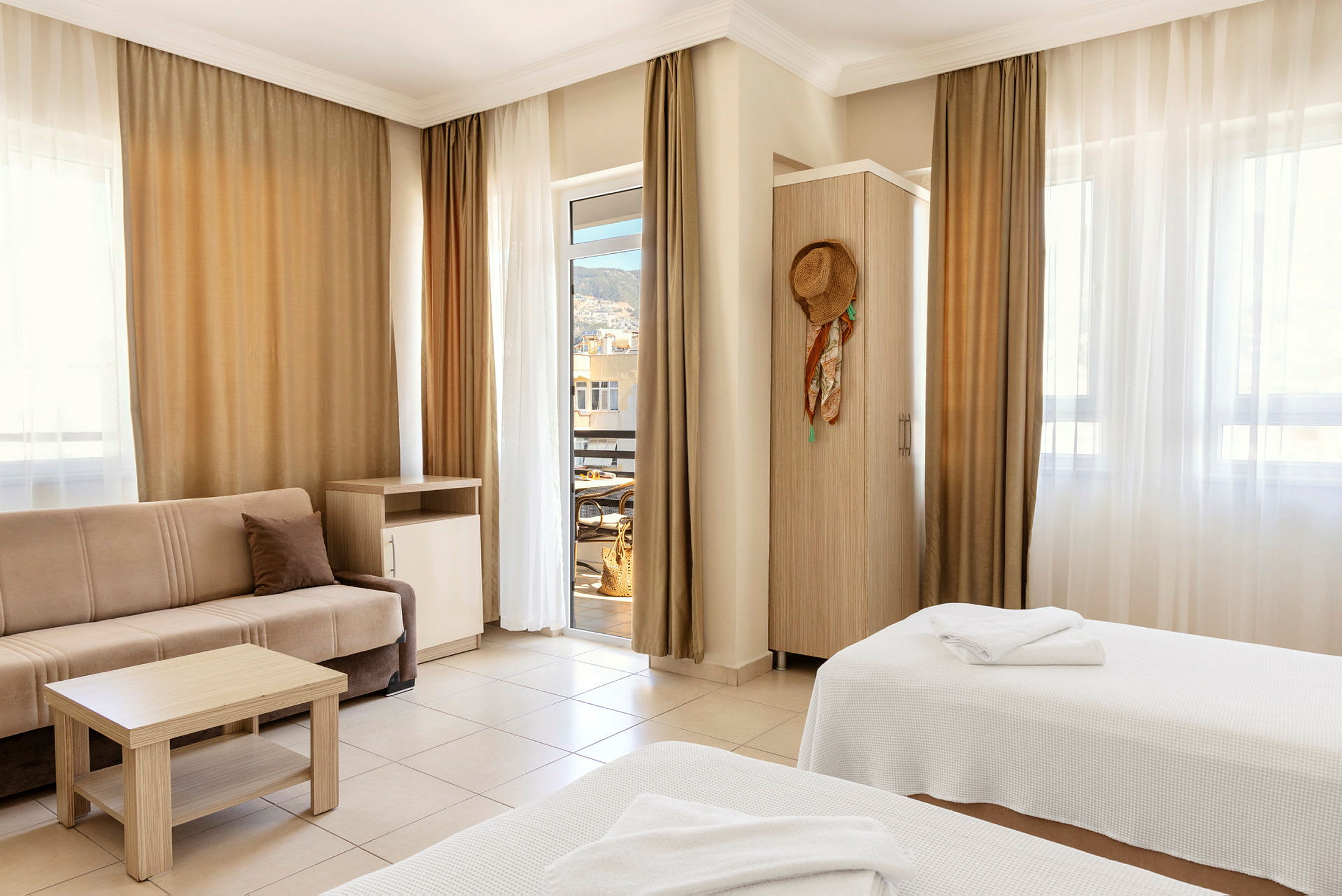 Ett hotellrum med två sängar, en soffa och balkongdörr. (AI-genererad text)