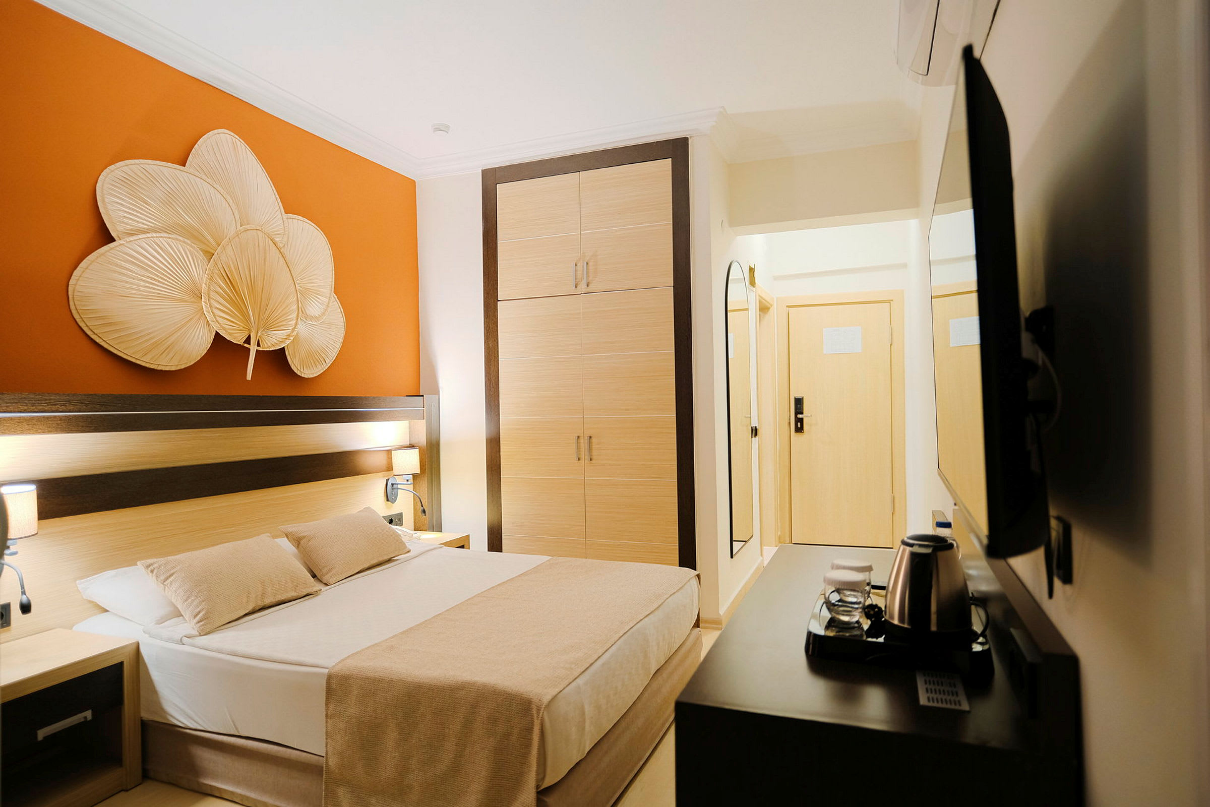 Ett hotellrum med en säng, garderob och orange väggdekoration. (AI-genererad text)