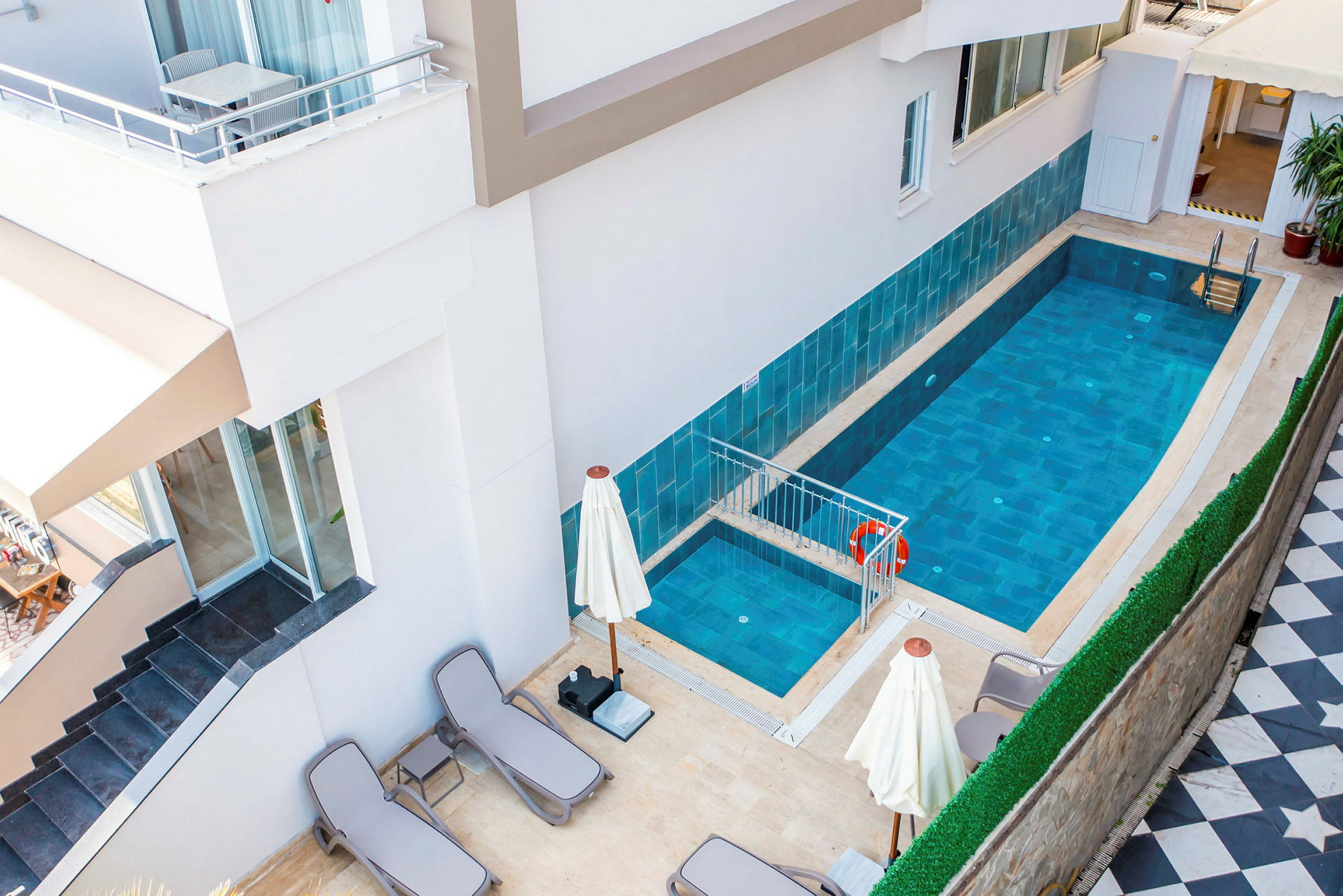 En liten pool vid ett hotell med solstolar och parasoller runt. (AI-genererad text)