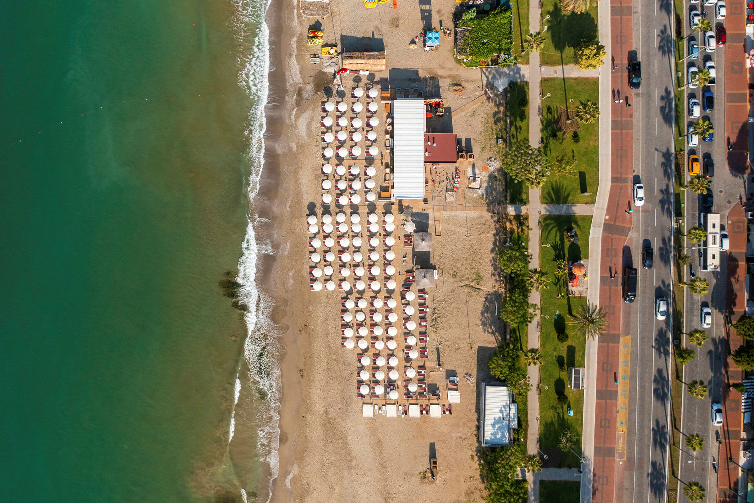 Flygfoto av en strand med parasoller och en gångväg bredvid. (AI-genererad text)