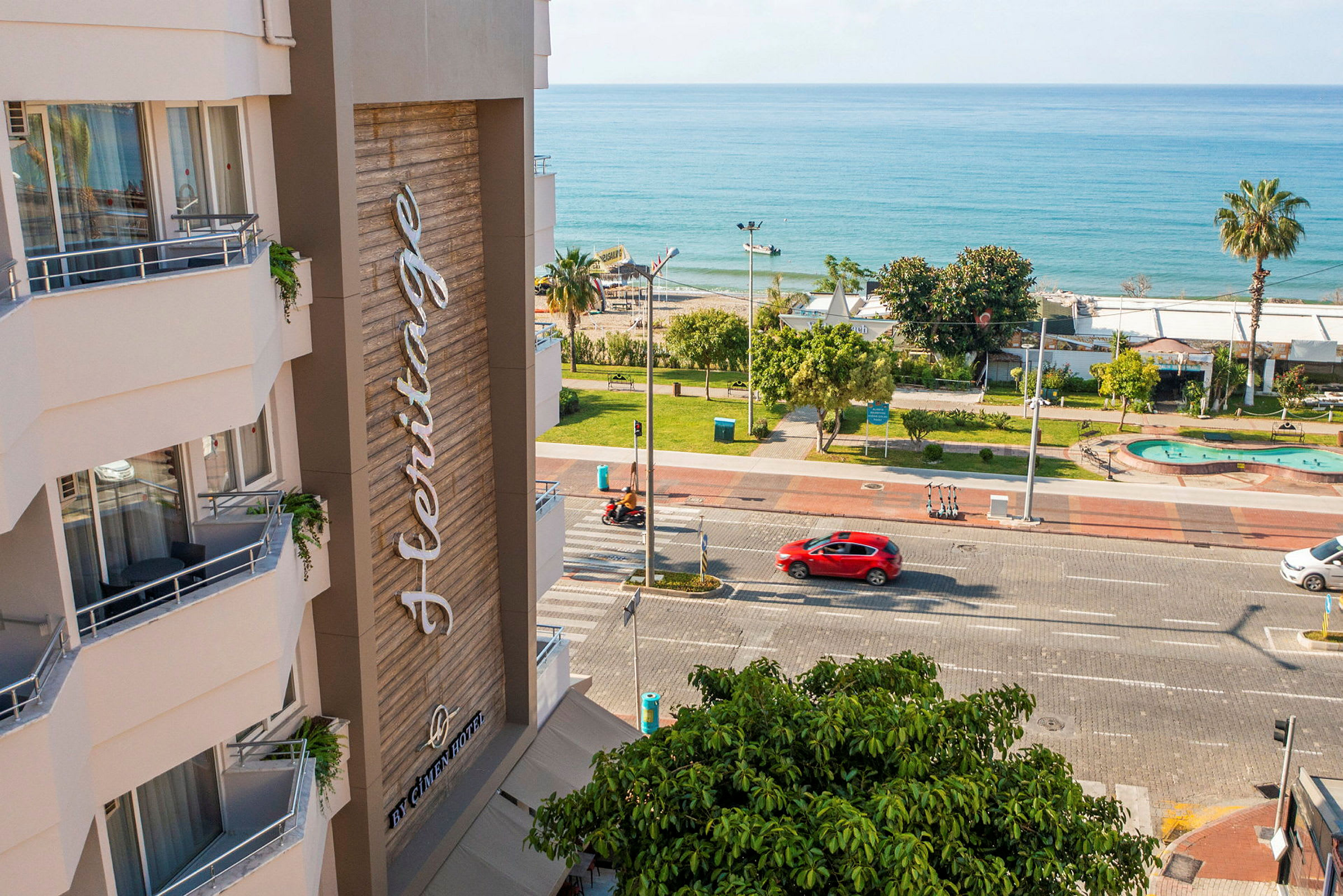 Ett hotell med namnet 'Heritage', en gata, en park och hav i bakgrunden. (AI-genererad text)