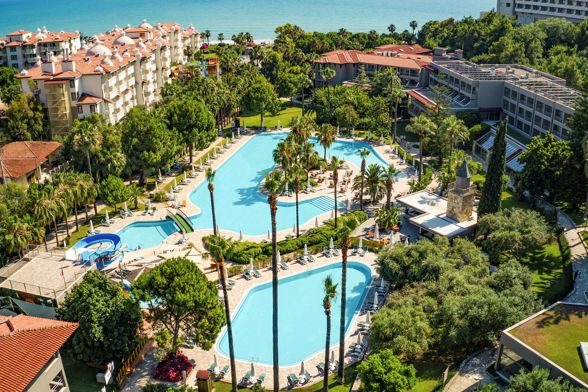 Vy över en hotellresort med pooler omgivna av grönska. (AI-genererad text)