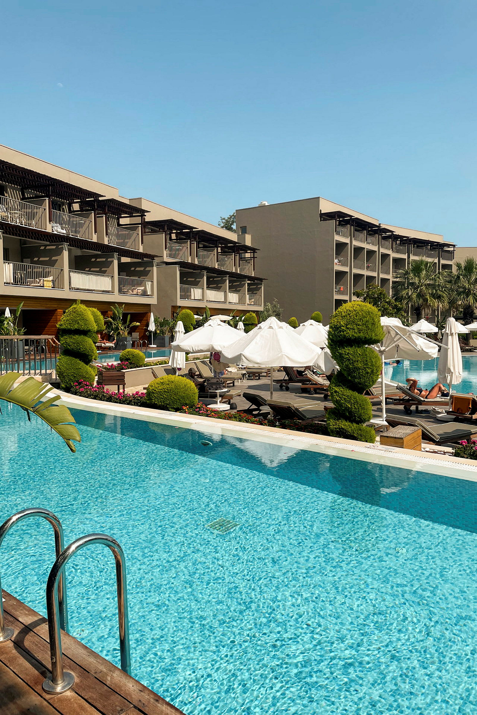 Ett hotell med poolområde och solstolar. (AI-genererad text)