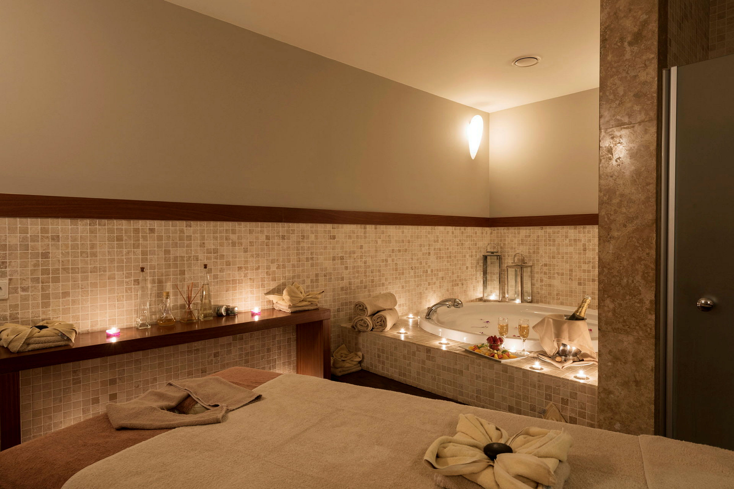 En spaavdelning med jacuzzi, bord med handdukar och prydnadsföremål. (AI-genererad text)