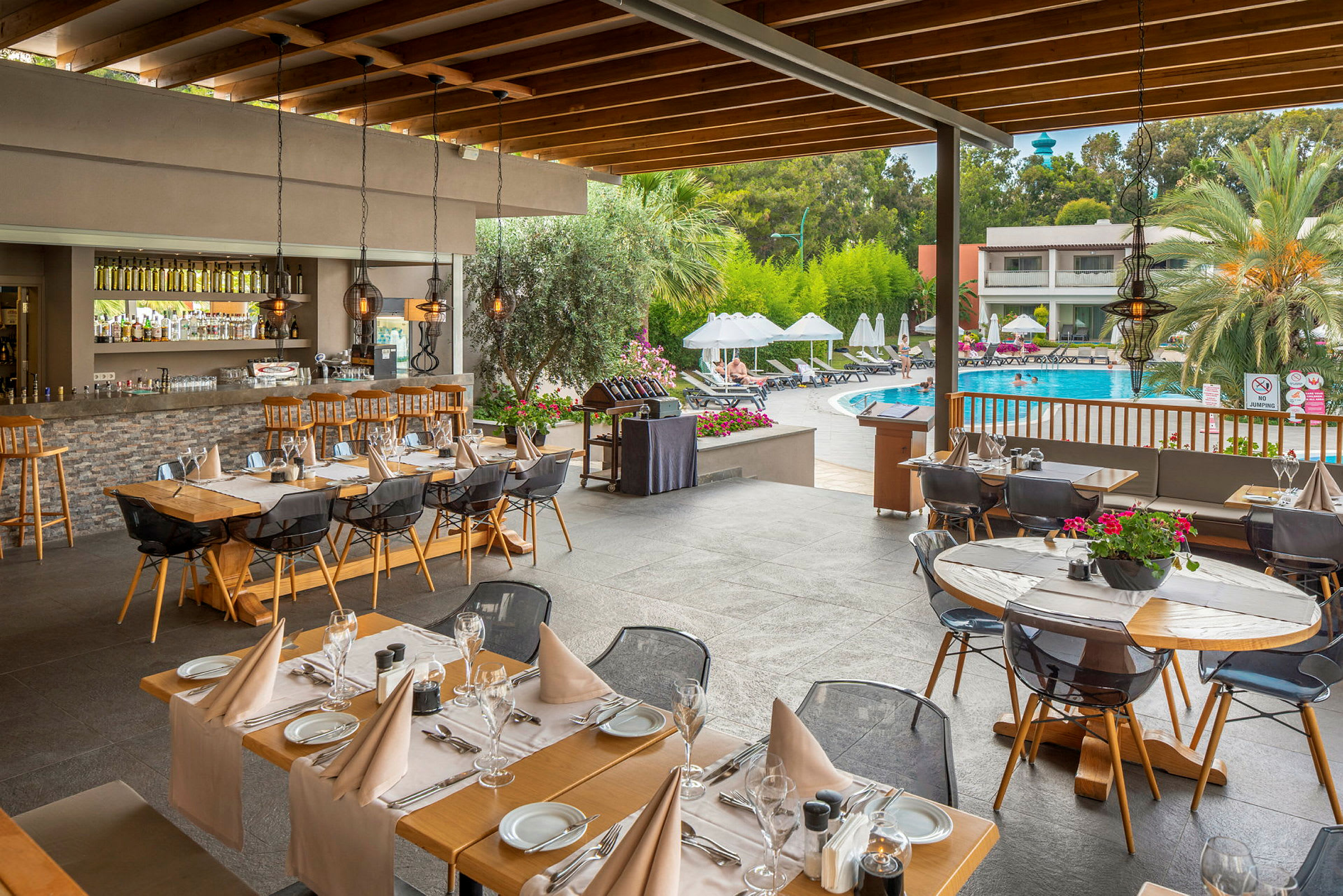 Utomhusrestaurang med dukade bord nära en pool. (AI-genererad text)