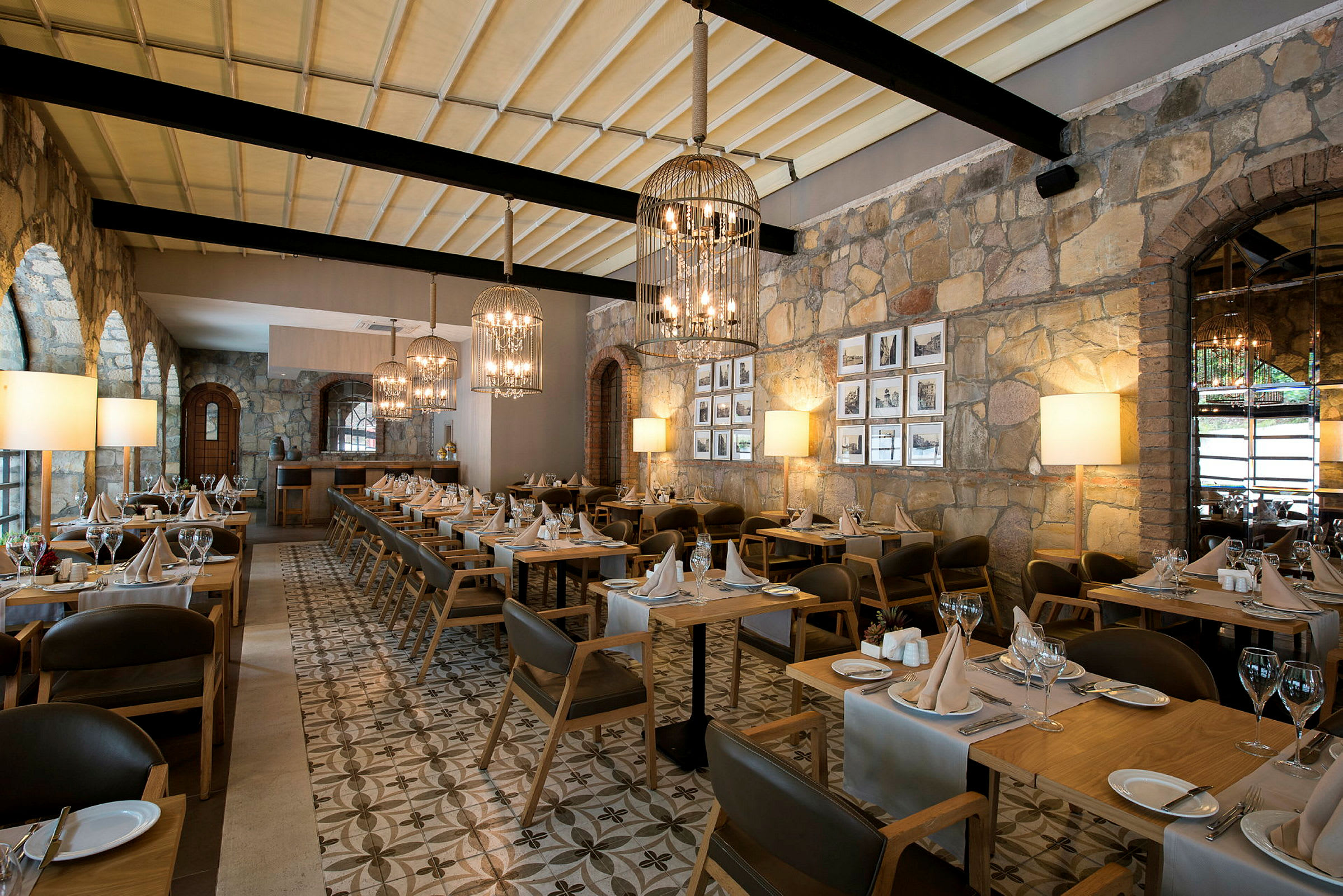 En restaurang med uppdukade bord och stolar, stenväggar och taklampor. (AI-genererad text)
