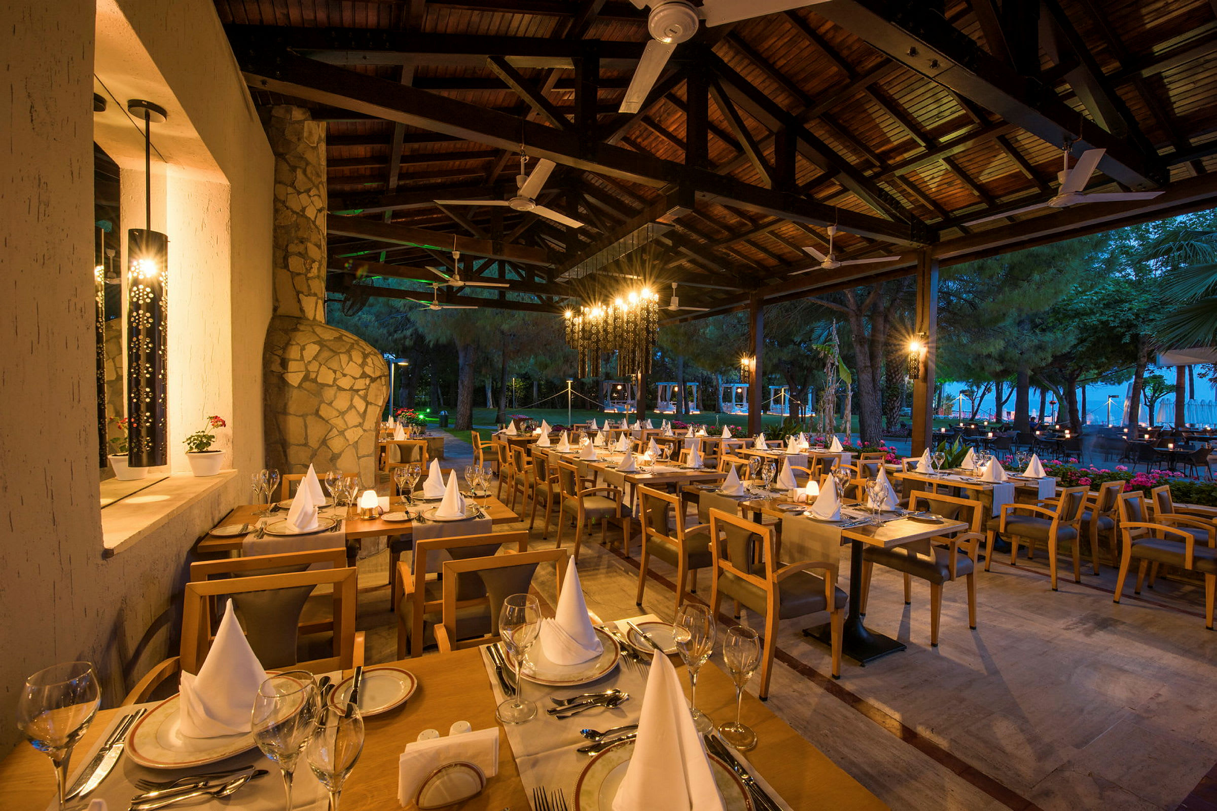 En utomhusrestaurang med dukade bord och stolar under en träpergola. (AI-genererad text)