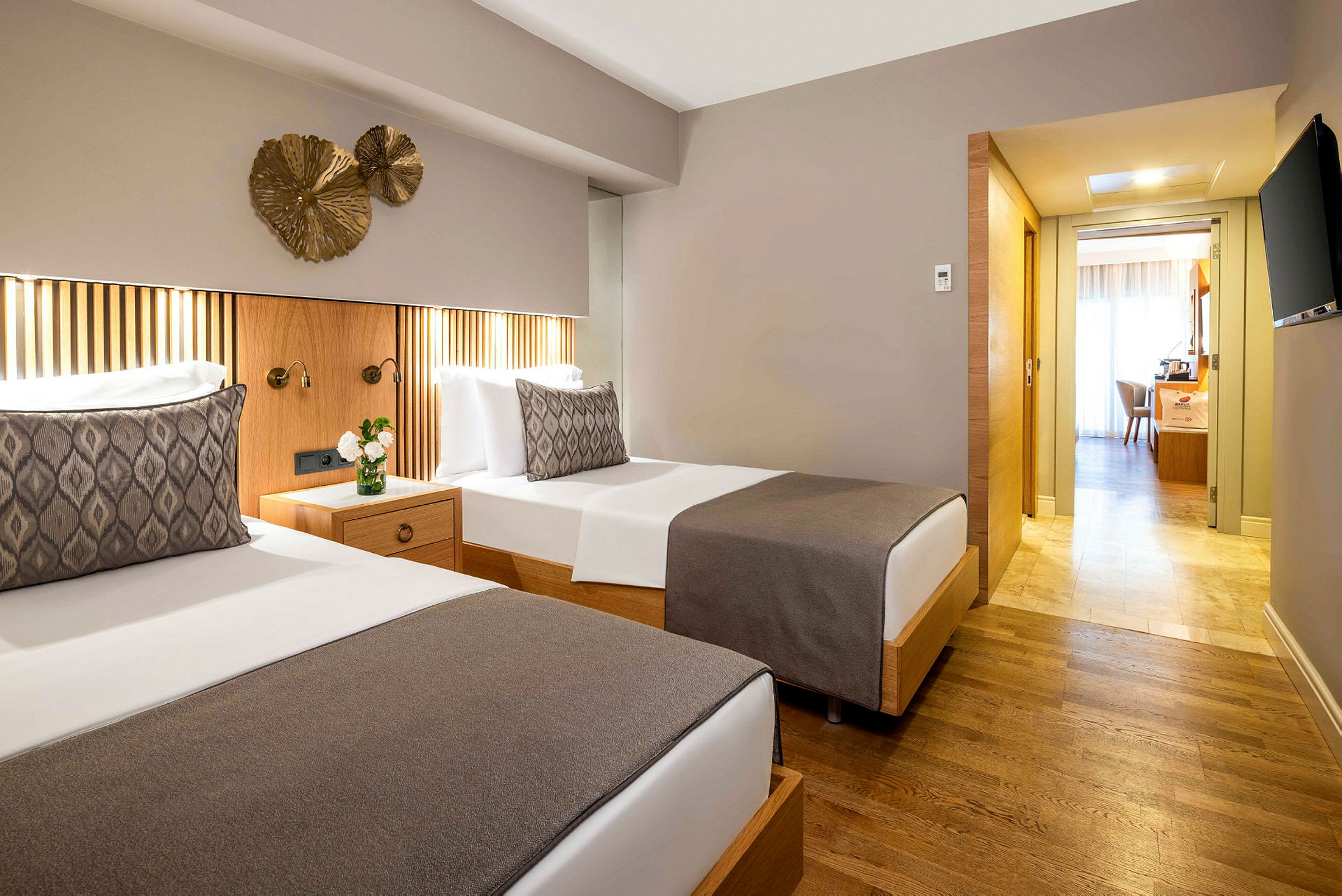 Två enkelsängar med neutralt överkast i ett hotellrum med trägolv och modern inredning. (AI-genererad text)