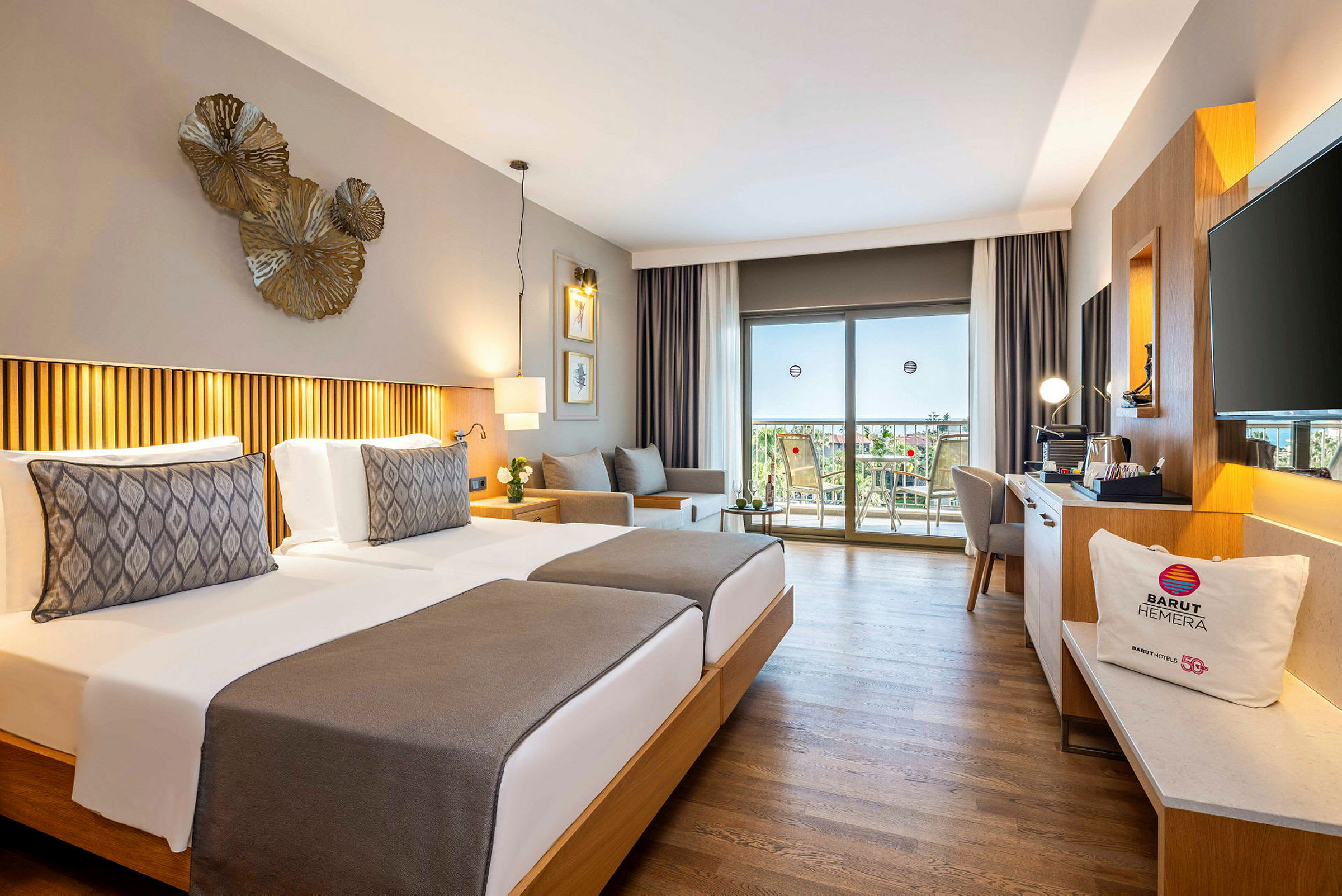 Hotellrum med två enkelsängar, dekorativ belysning och utsikt mot en balkong med möbler. (AI-genererad text)