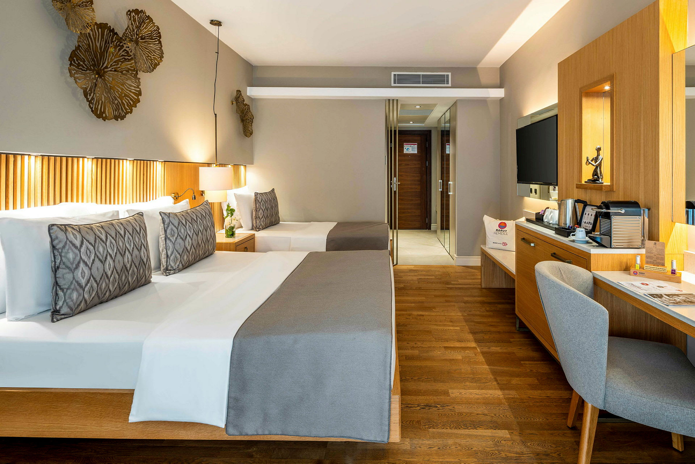 En hotellrum med två sängar, skrivbord, stol och spegel. (AI-genererad text)