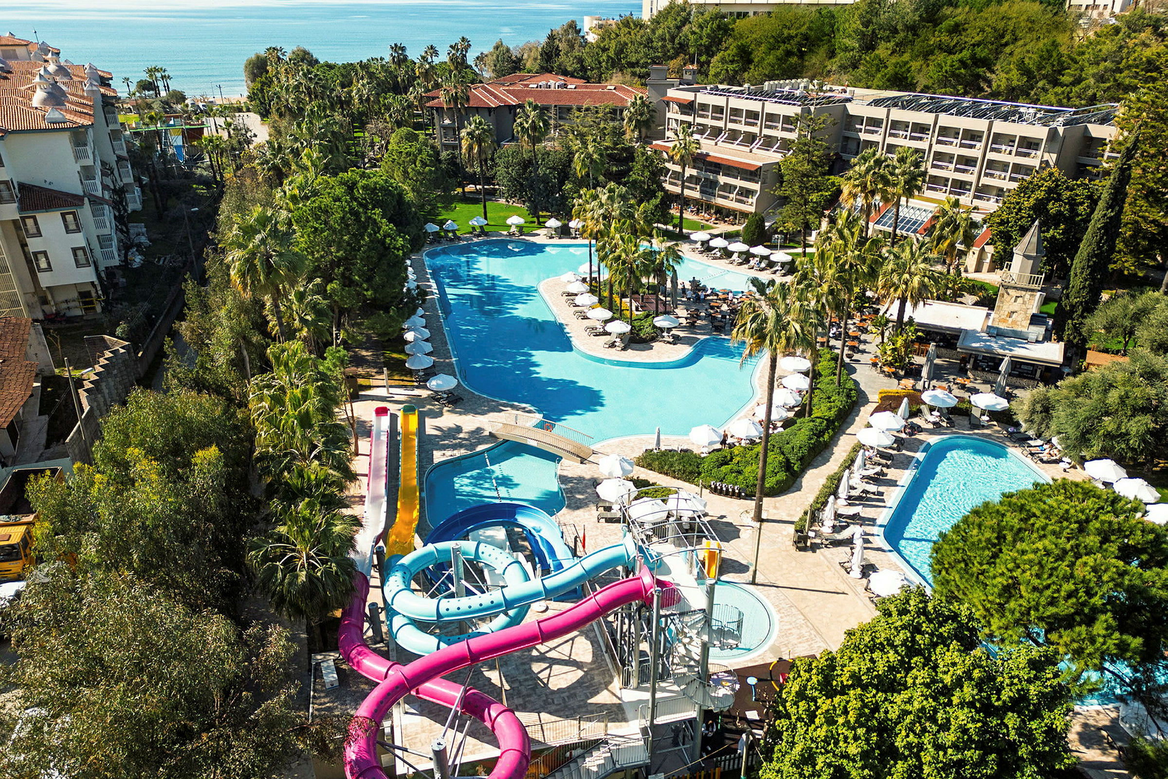 Vy över en resort med flera pooler och vattenrutschbanor, omgiven av grönska. (AI-genererad text)