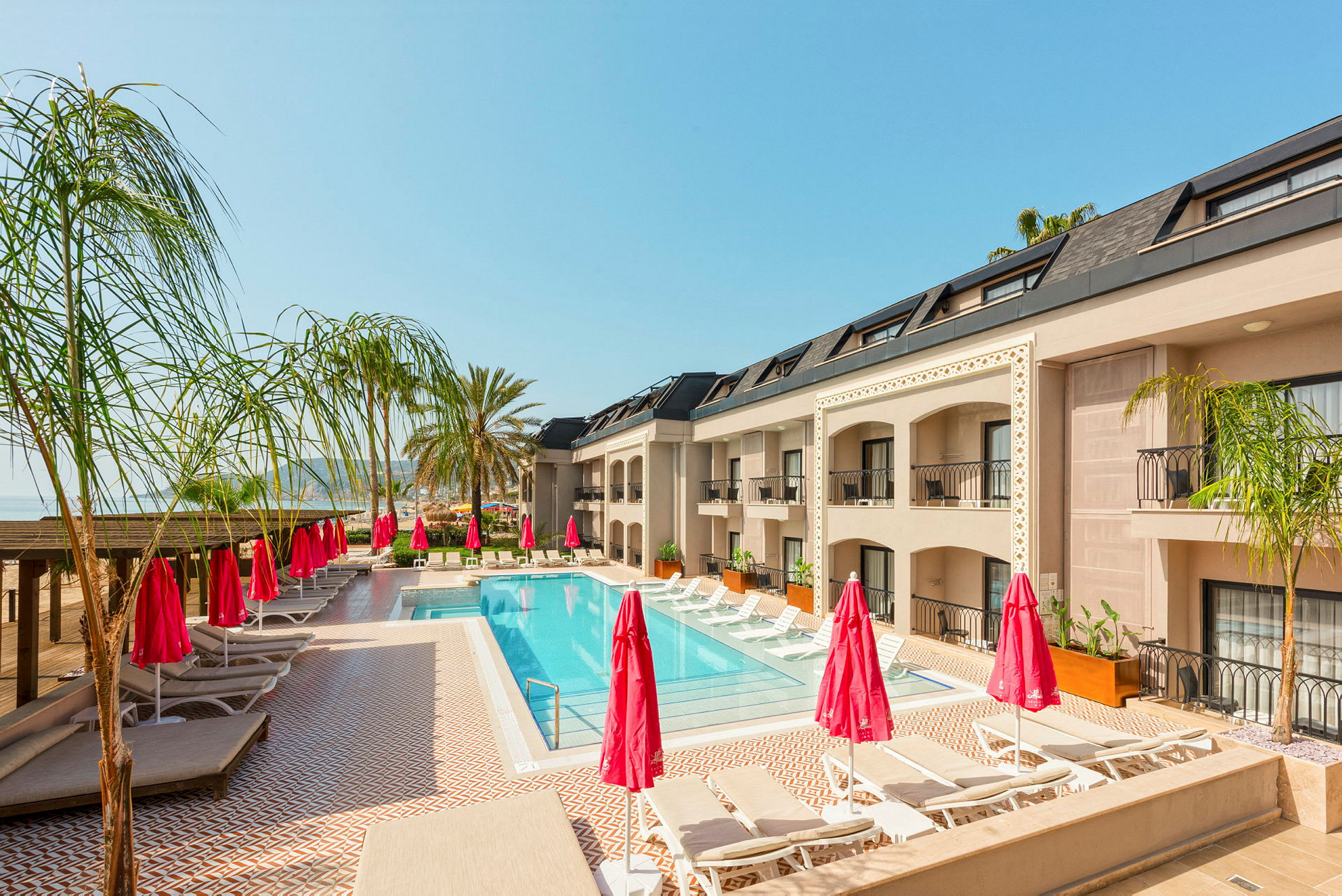 Poolområde med solsängar och parasoller vid hotellbyggnad. (AI-genererad text)