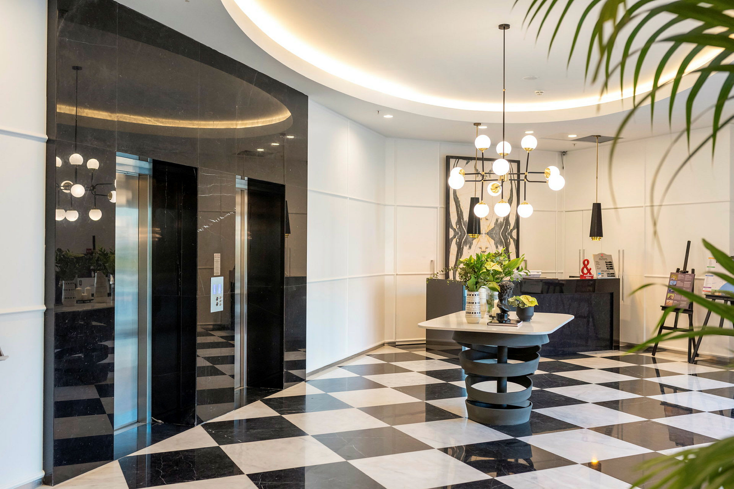 Entréhall med svartvit rutigt golv, hissar och modern inredning. (AI-genererad text)
