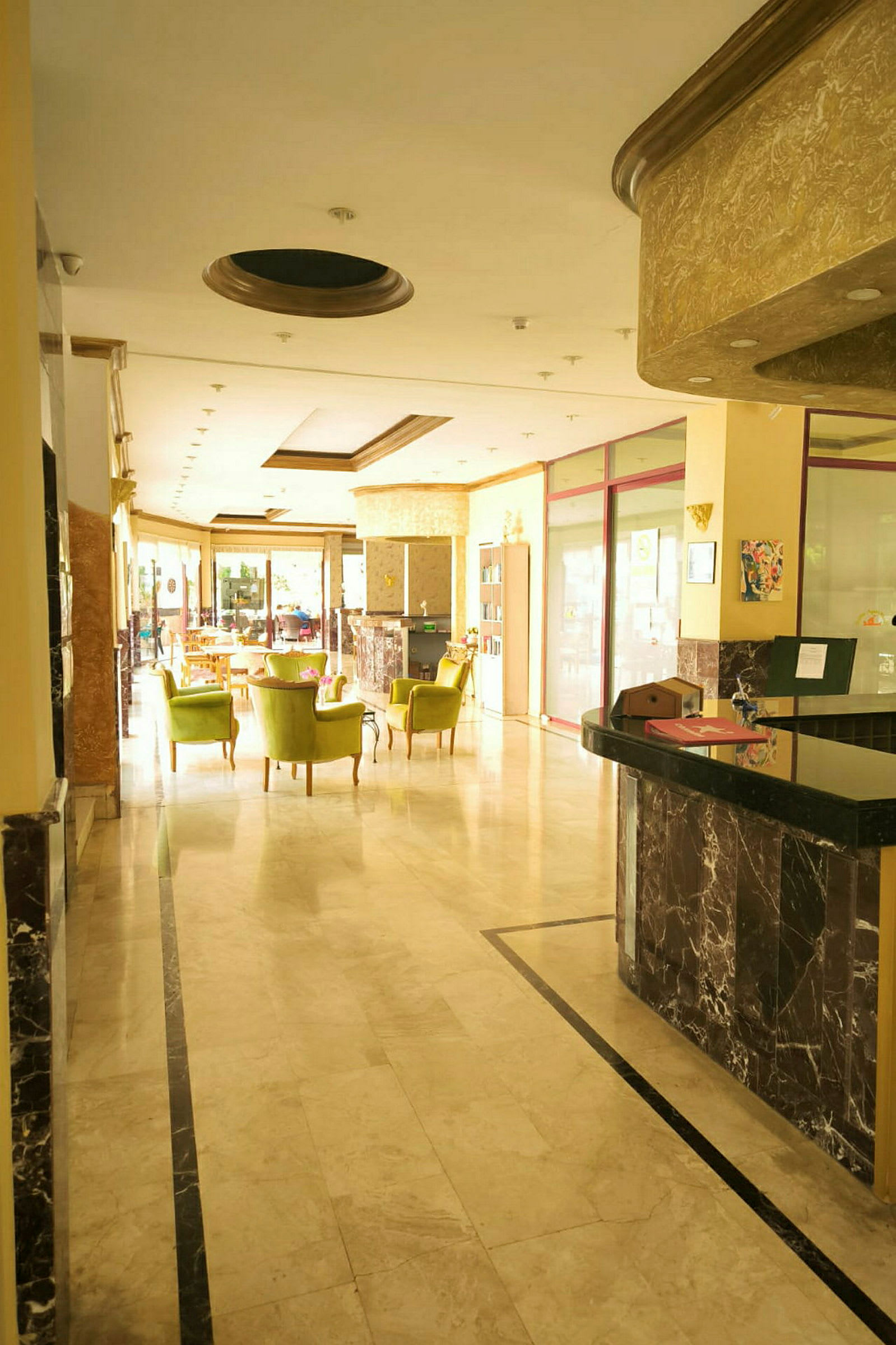 Hotellets reception med marmorgolv och grönklädda stolar. (AI-genererad text)