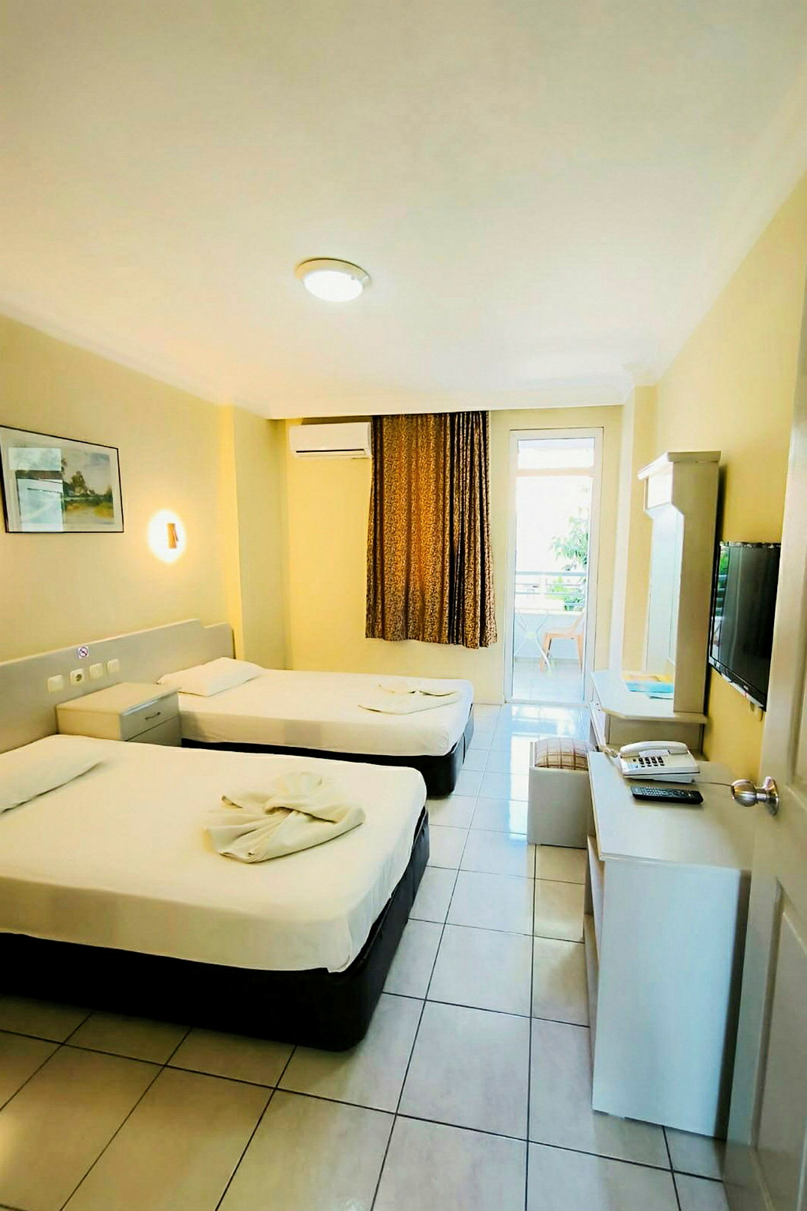 Hotellrum med två enkelsängar, skrivbord och TV. (AI-genererad text)