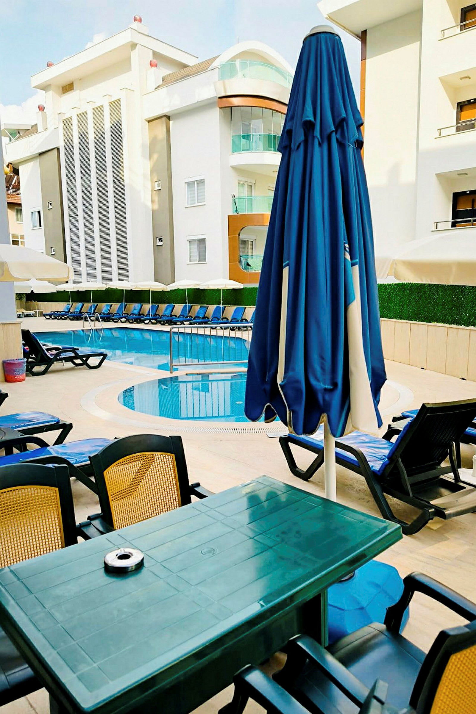 Solstolar och parasoller vid poolområdet utanför ett hotell. (AI-genererad text)