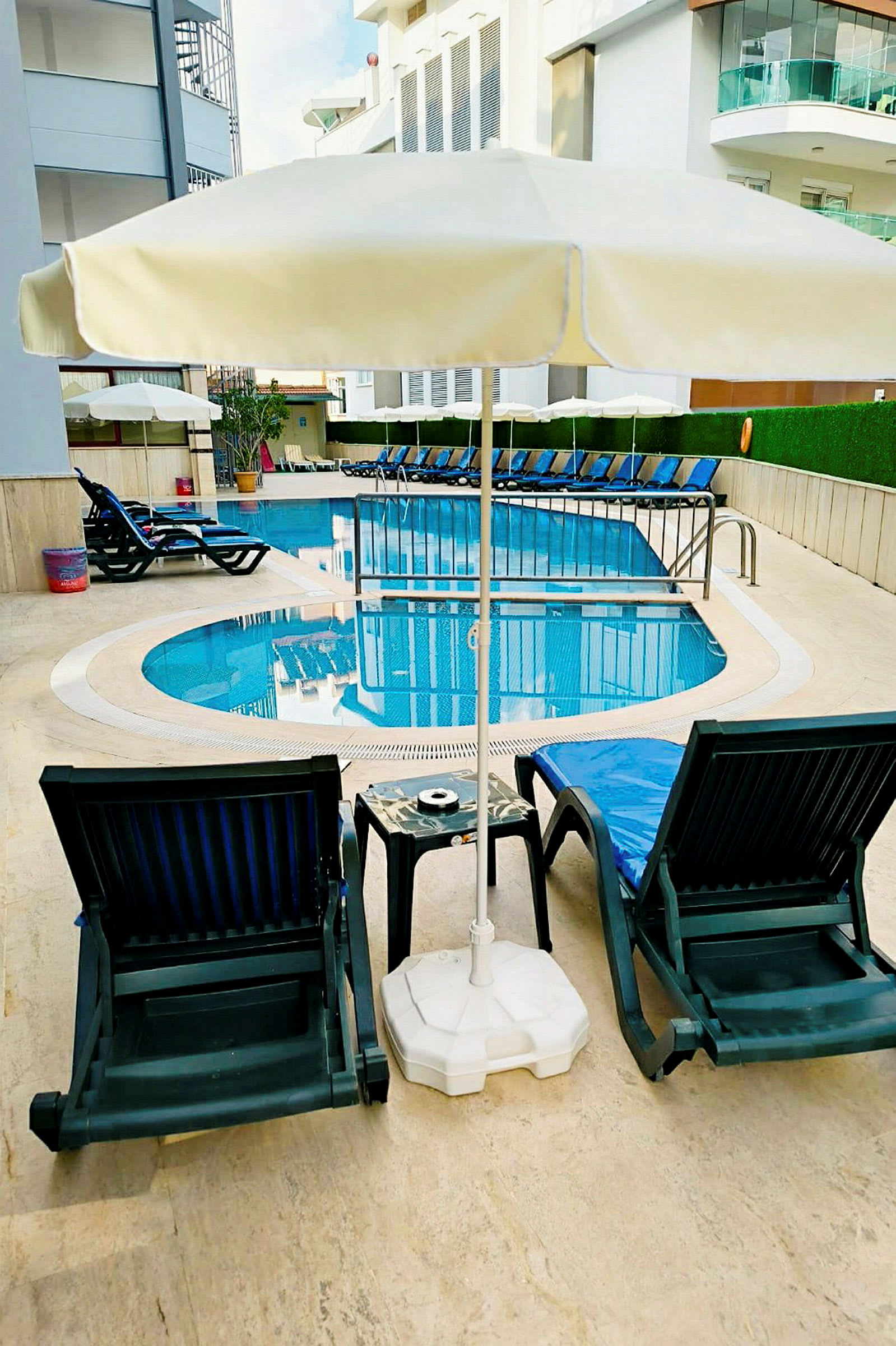 Två solstolar med ett parasoll framför en pool. (AI-genererad text)