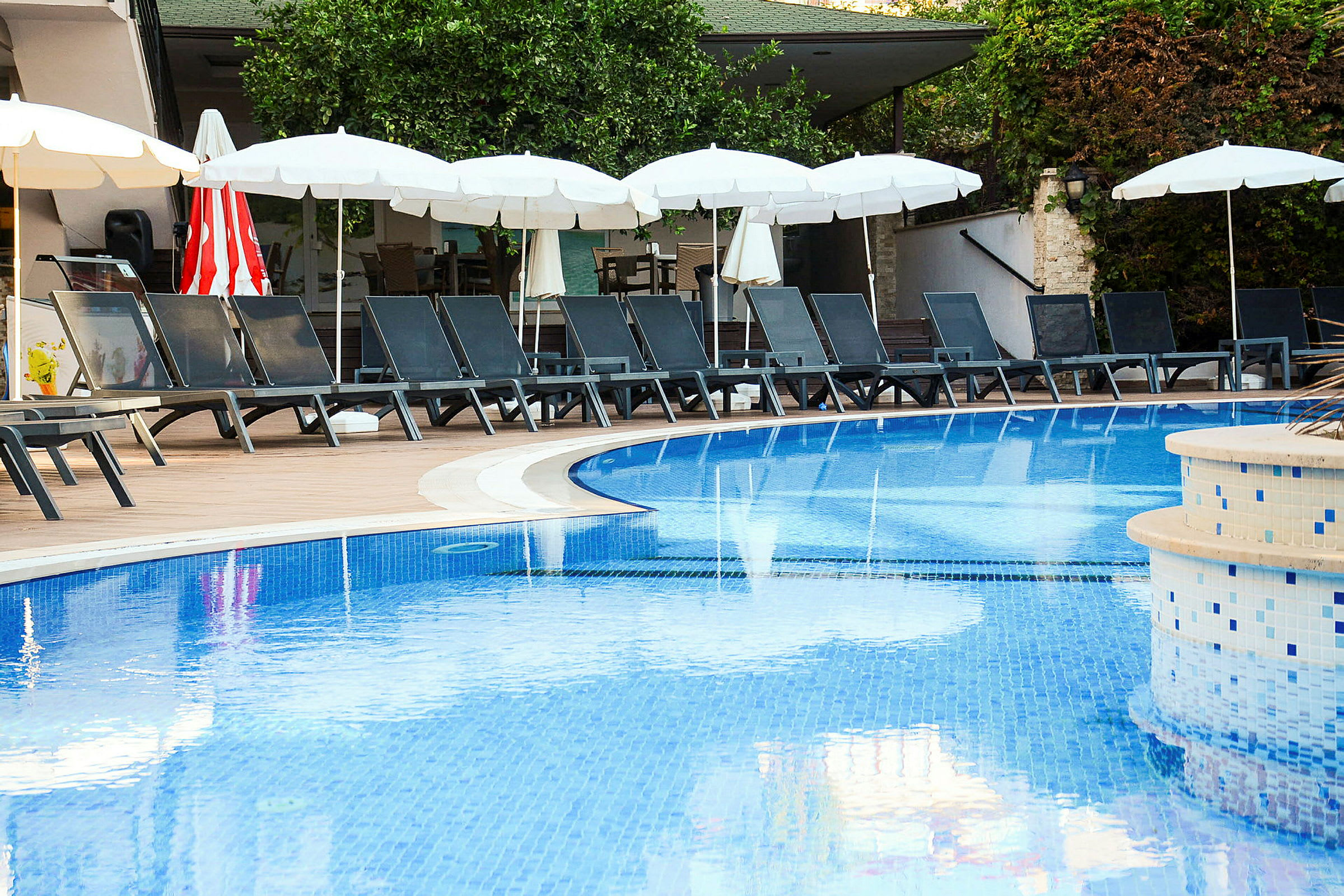 Pool med solstolar och parasoller i bakgrunden. (AI-genererad text)