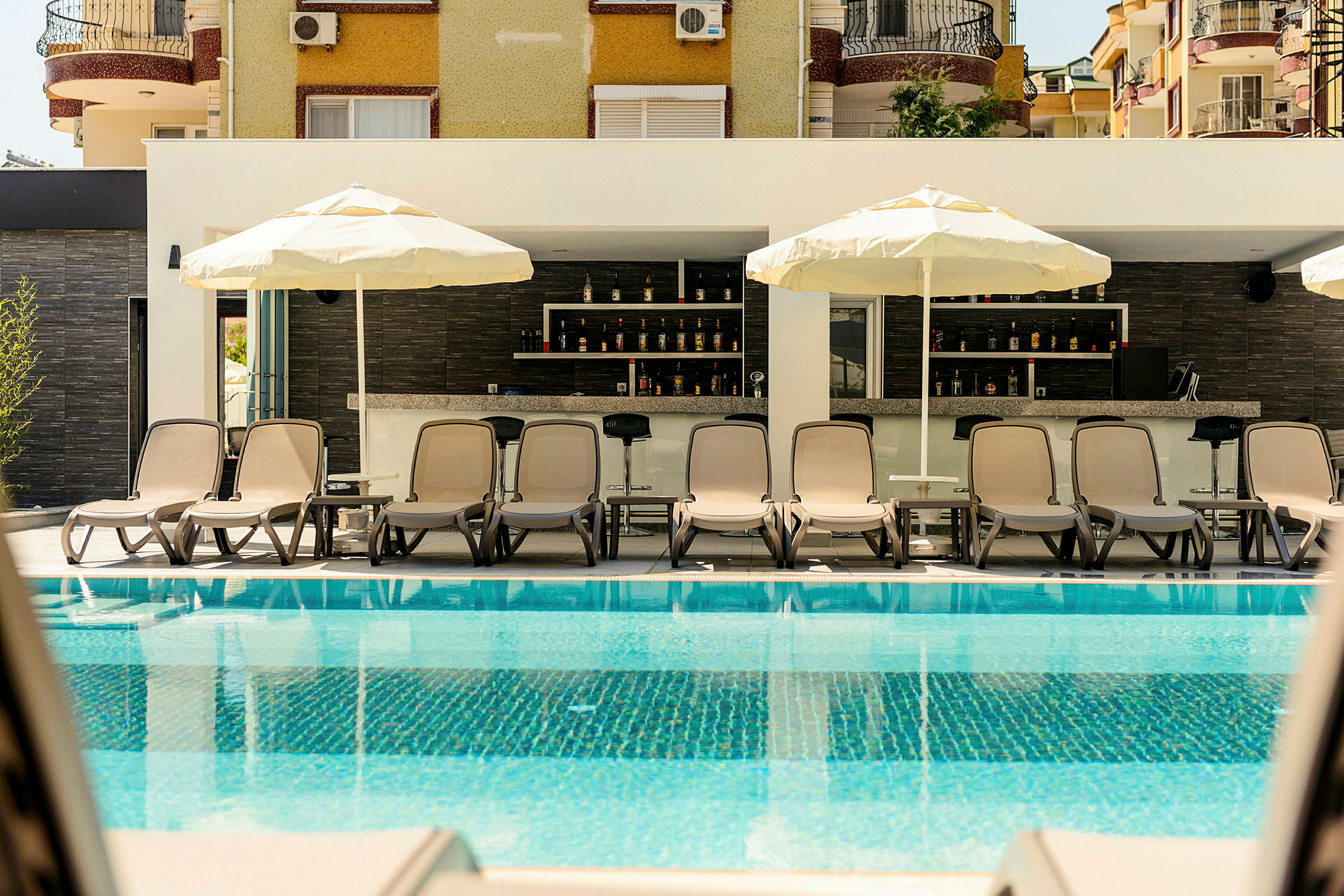 Solstolar och parasoller vid en pool med en bar i bakgrunden. (AI-genererad text)
