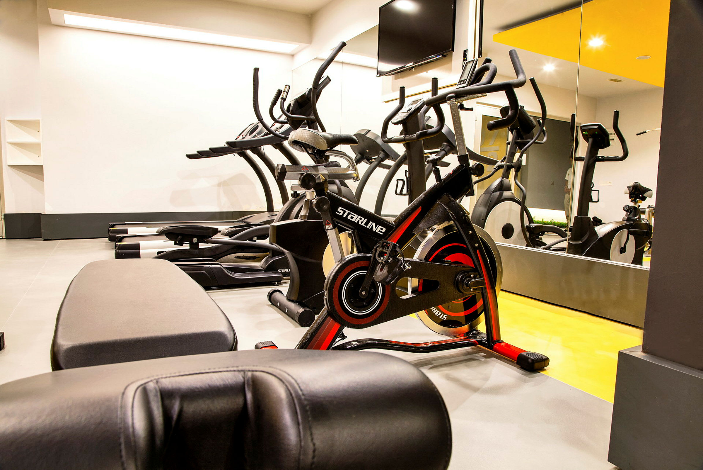 Ett gym med träningsmaskiner och speglar på väggen. (AI-genererad text)