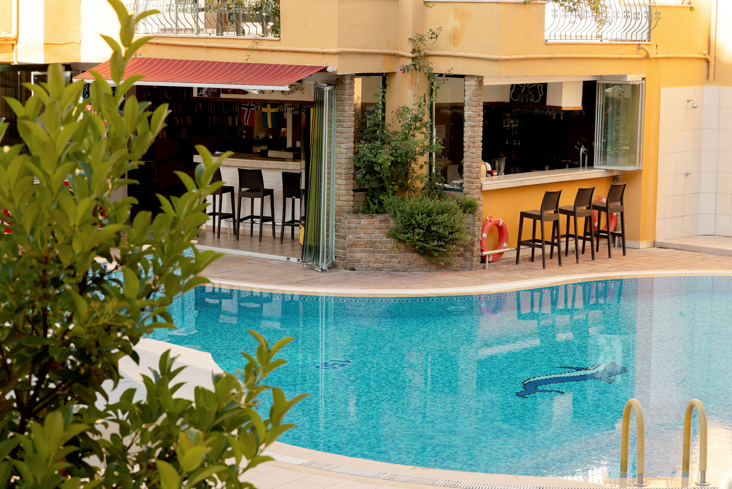 En pool framför en byggnad med en bar och stolar. (AI-genererad text)