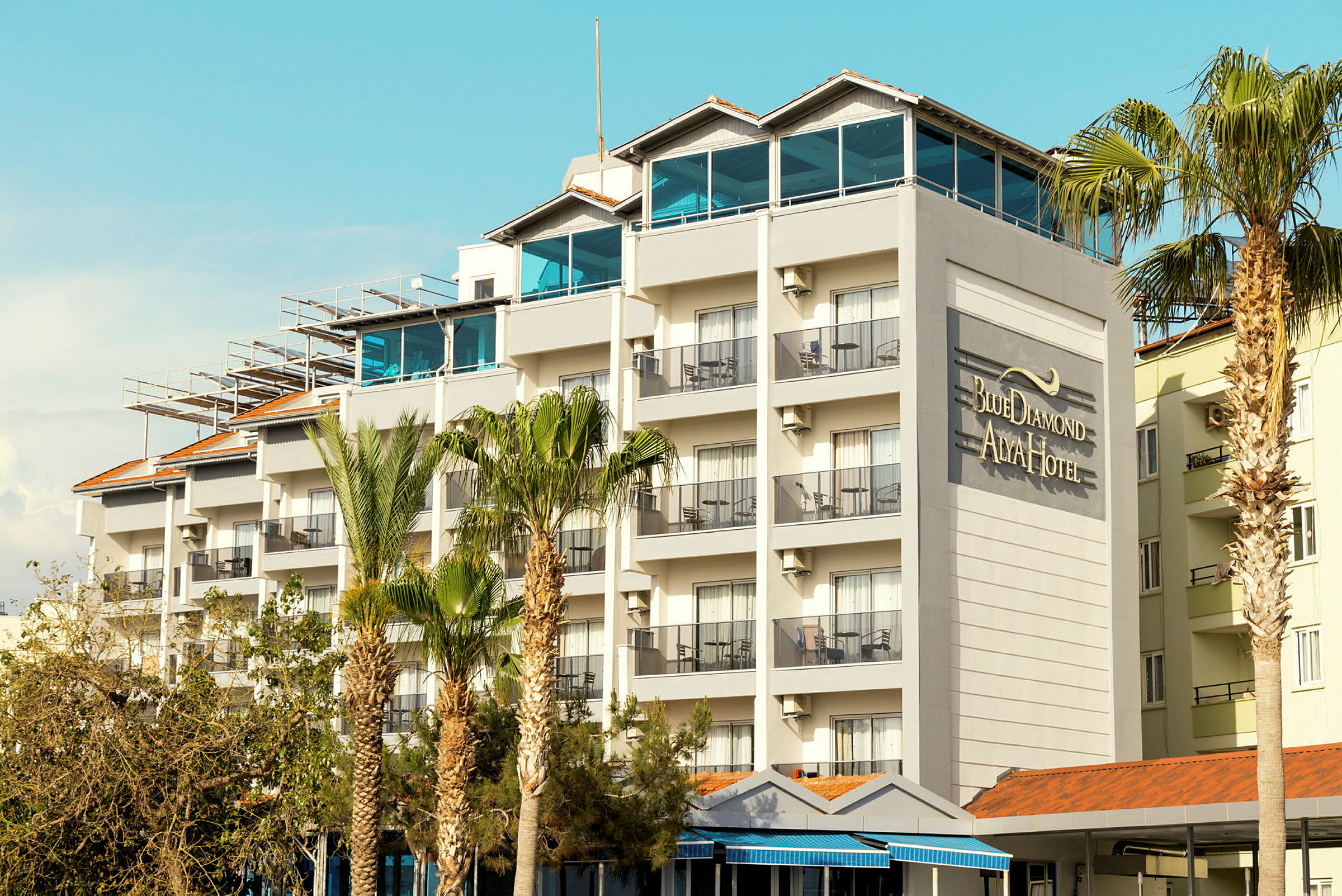 En hotellbyggnad med flera våningar och balkonger, samt texten "Blue Diamond Alya Hotel" på väggen. (AI-genererad text)