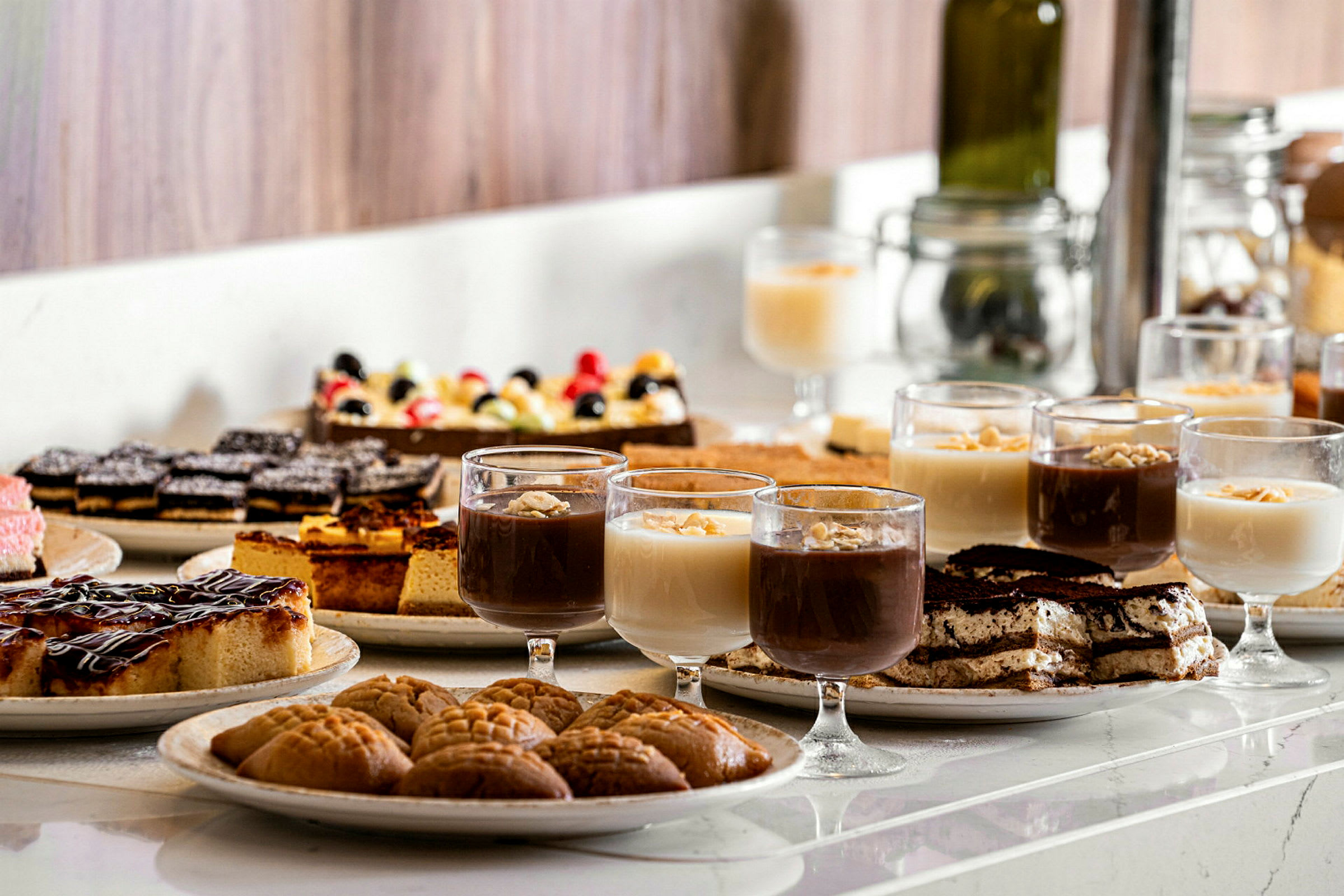 Ett bord med olika desserter, inklusive glas med mousse och bakverk. (AI-genererad text)