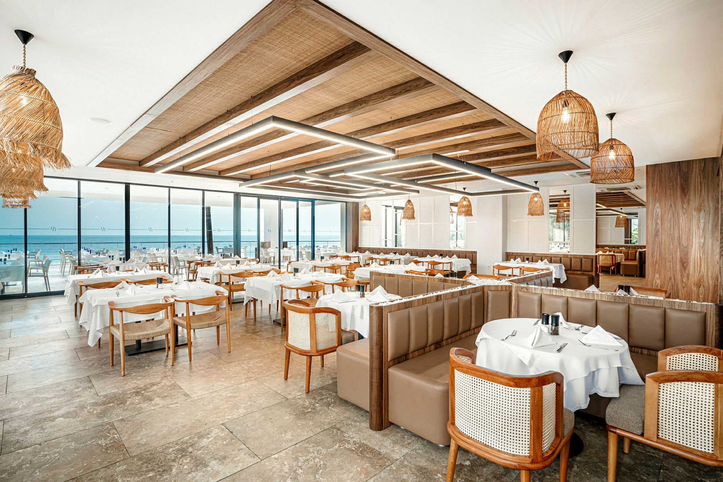 Restaurang med bord klädda i vita dukar och utsikt över havet. (AI-genererad text)