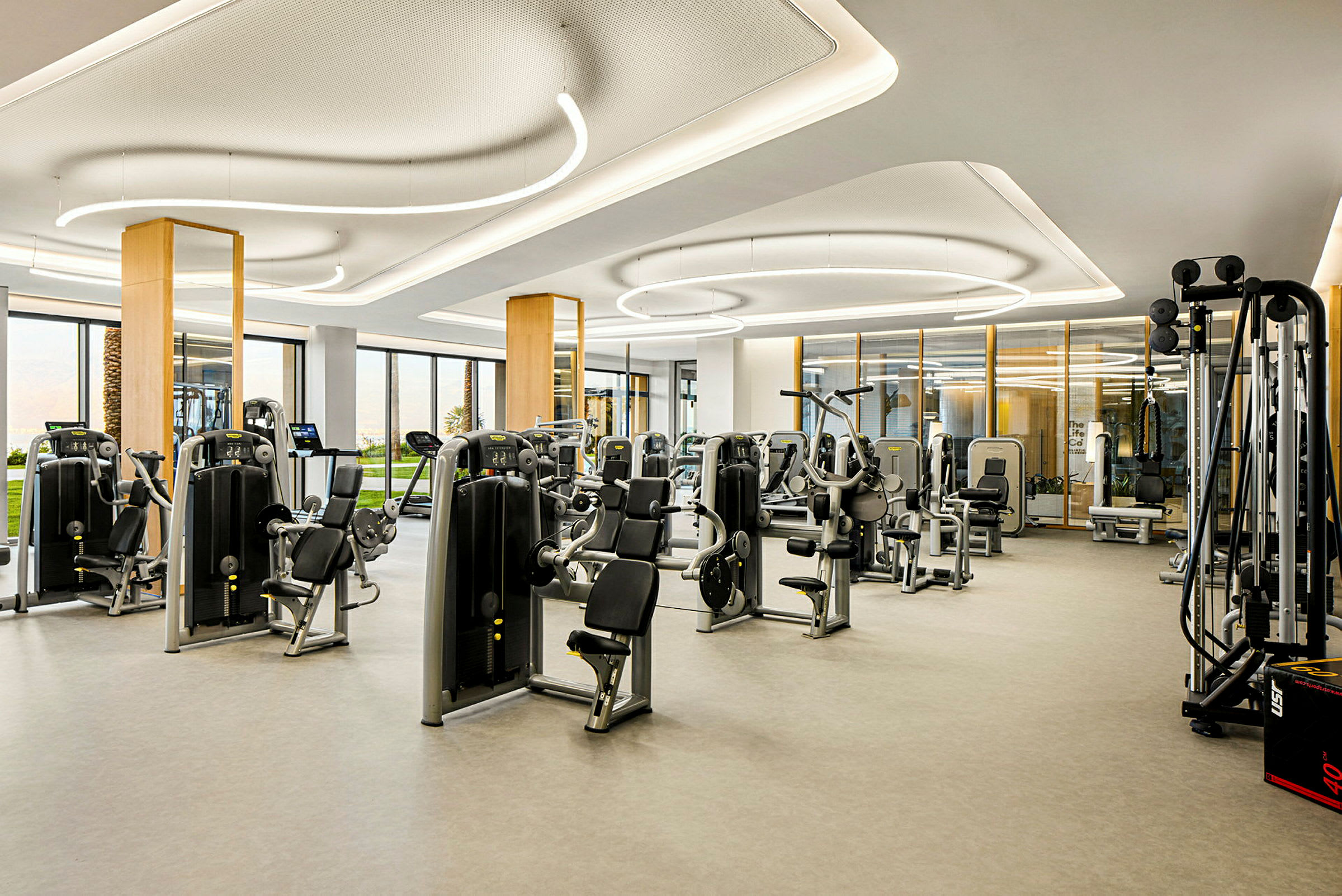 Ett gym med moderna träningsmaskiner och stora fönster. (AI-genererad text)
