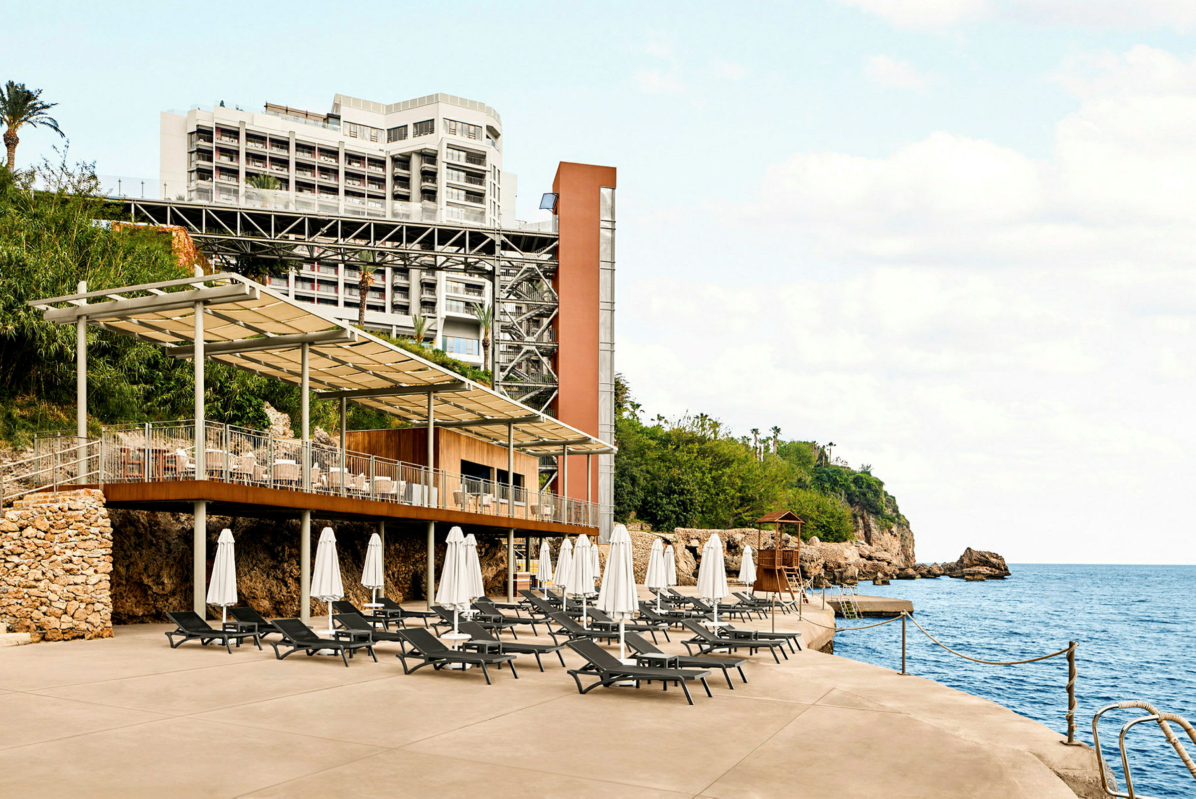 Hotell med terrass och solstolar vid havet. (AI-genererad text)