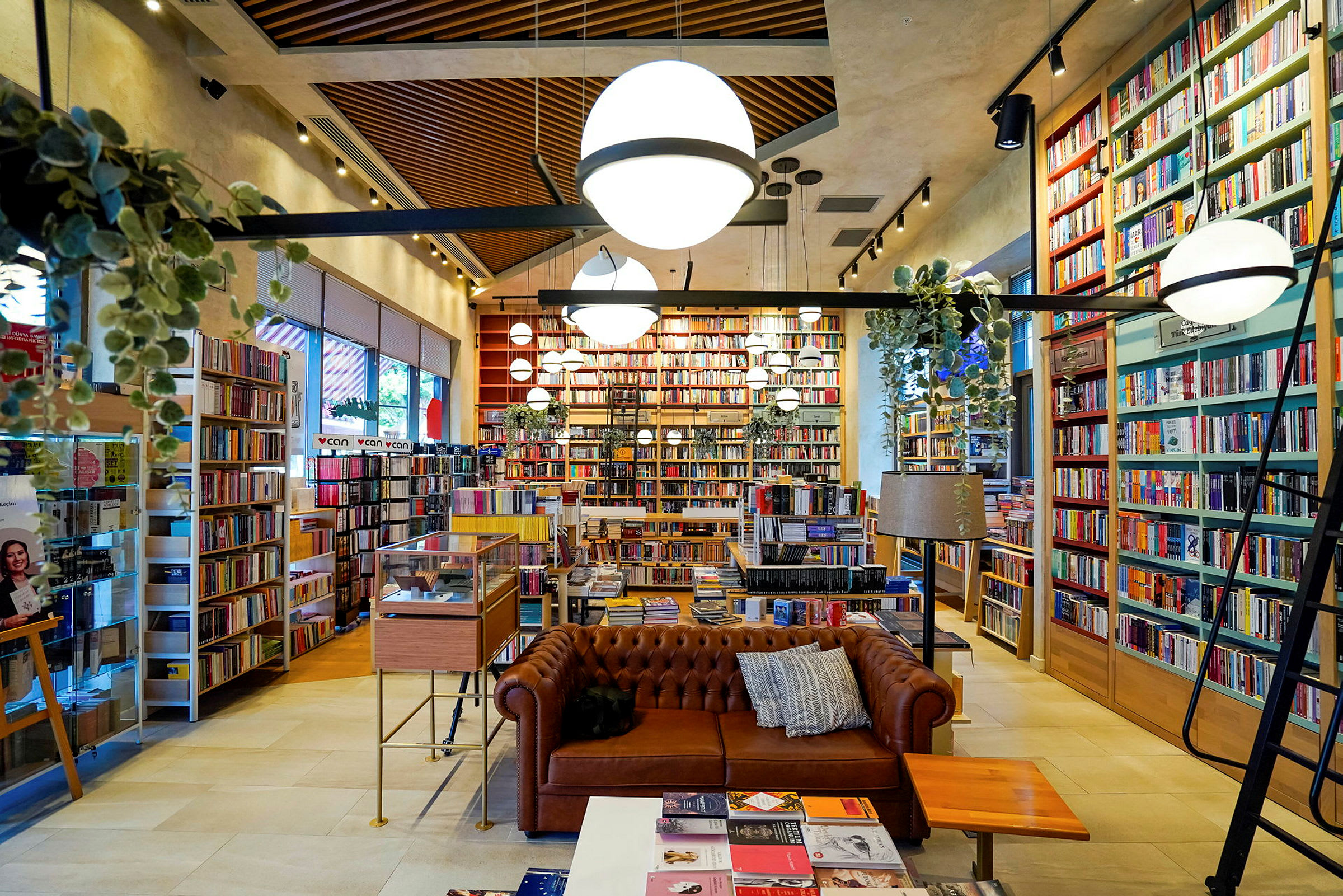 Ett välorganiserat bibliotek eller bokhandel med en brun soffa och många bokhyllor fyllda med böcker. (AI-genererad text)