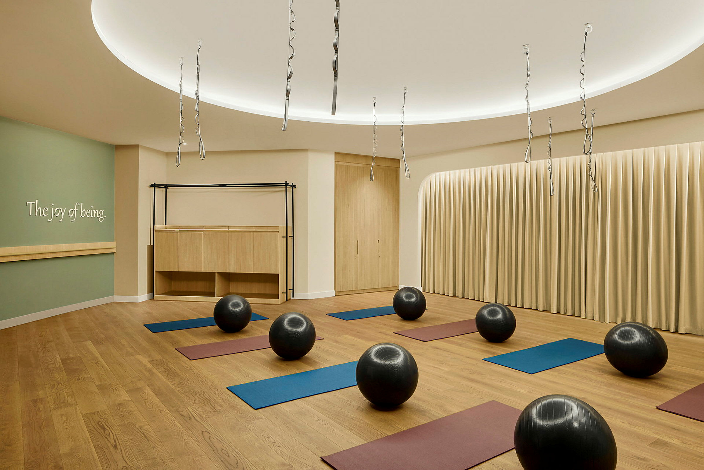 Ett yoga- eller träningsrum med träningsmattor och balansbollar jämnt utspridda på ett trägolv. (AI-genererad text)