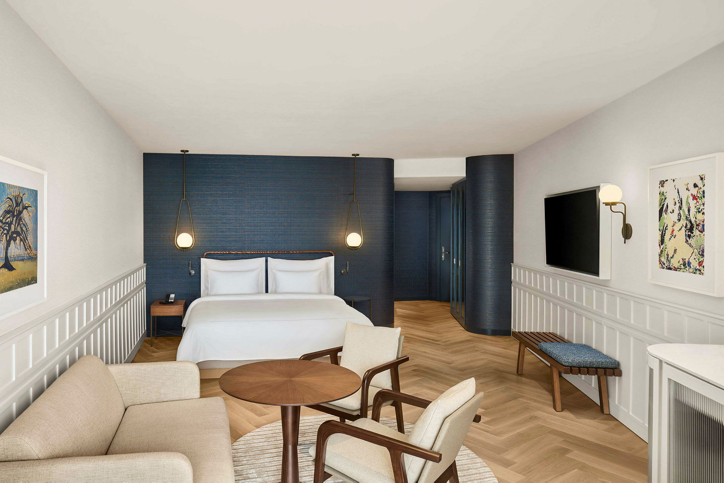 Ett hotellrum med en dubbelsäng, en sittgrupp, och en modern design med blå väggar och ljusa trädetaljer. (AI-genererad text)
