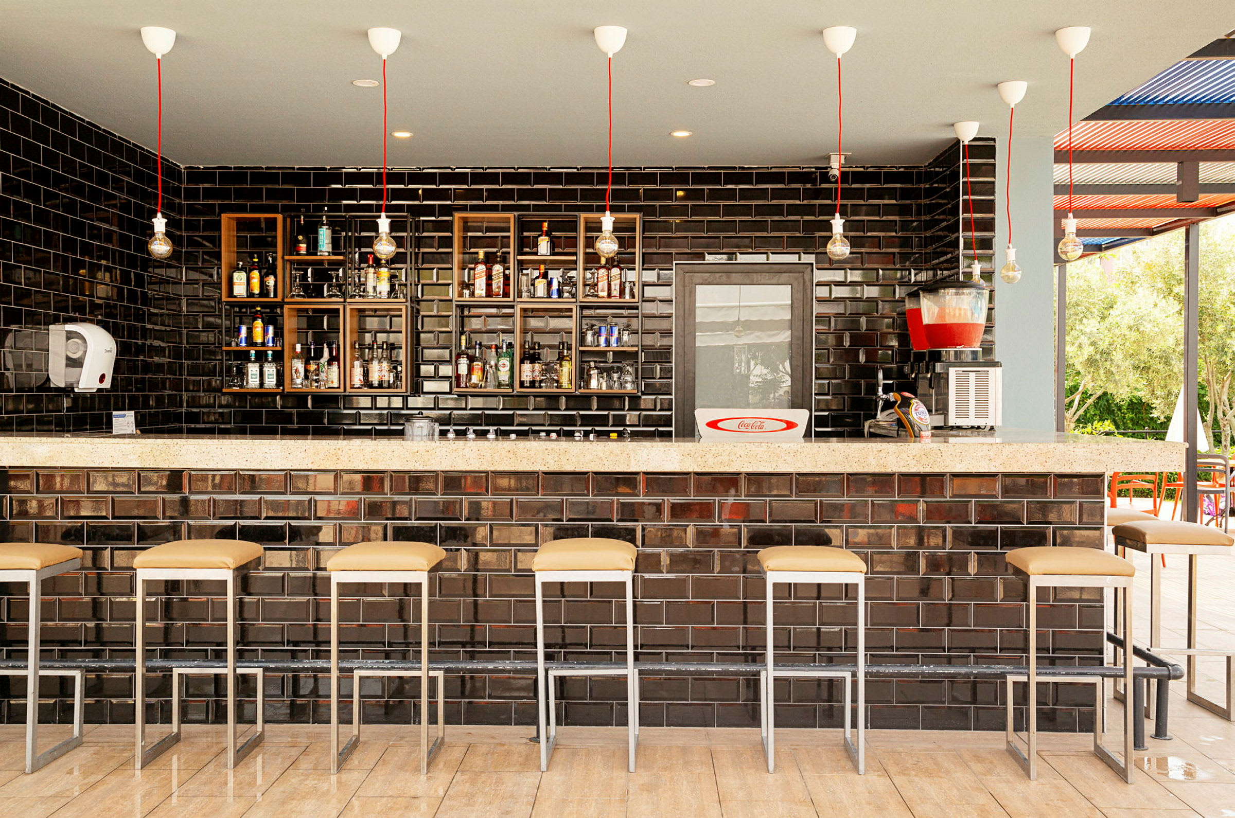 En bar med svarta kakelväggar och rad av barstolar. (AI-genererad text)