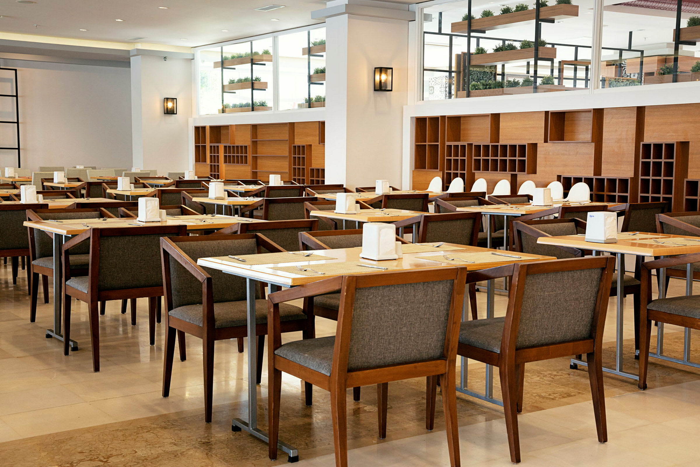 Restaurang med flera bord och stolar av trä, inredd med hyllor och dekorationer. (AI-genererad text)