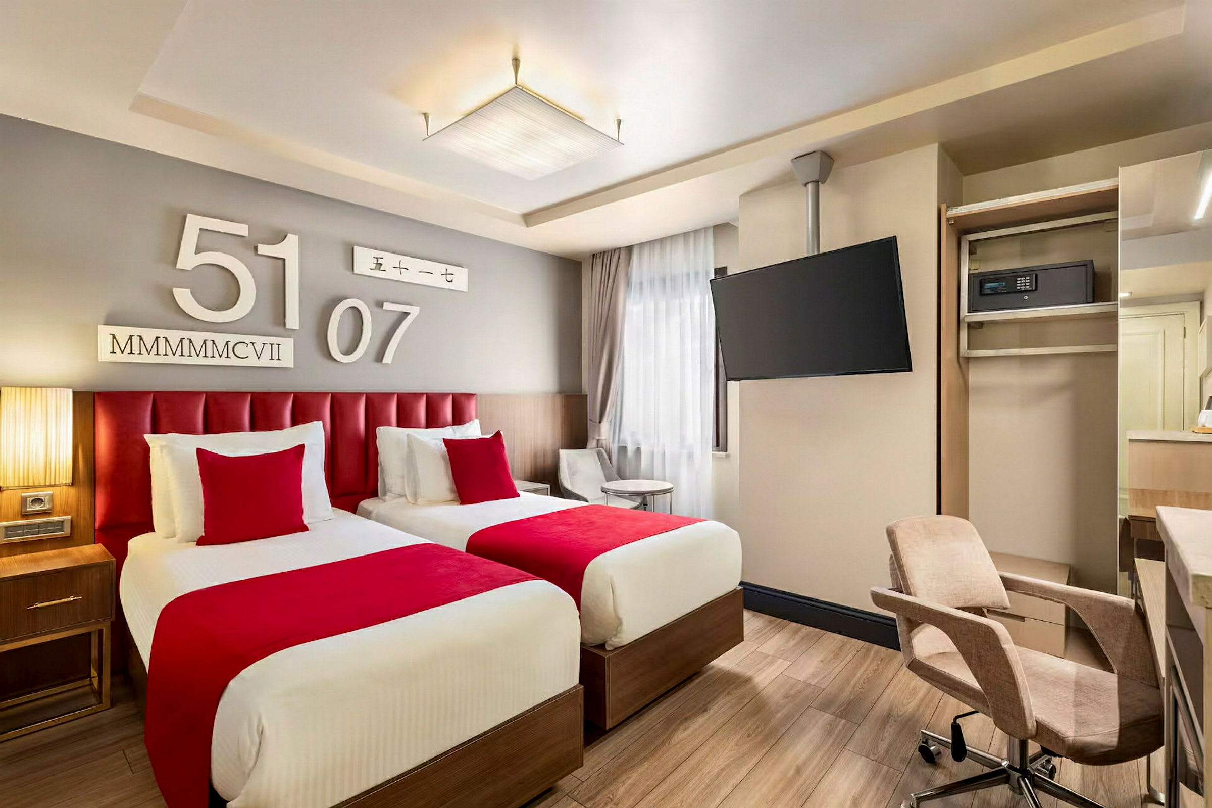 Två enkelsängar med röda sängkläder i ett modernt hotellrum. (AI-genererad text)