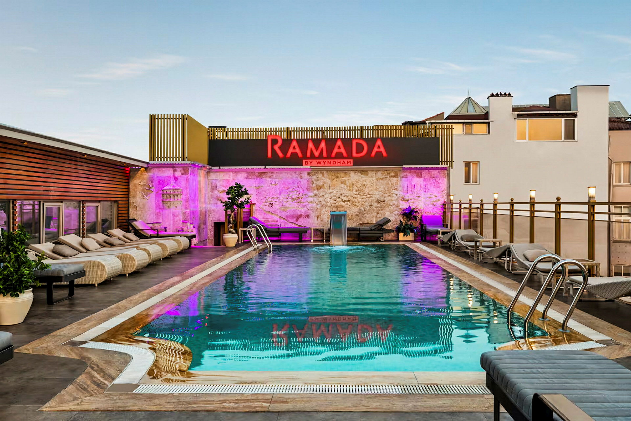Bild av en utomhuspool med solstolar runt om och ett skylt med texten Ramada by Wyndham. (AI-genererad text)