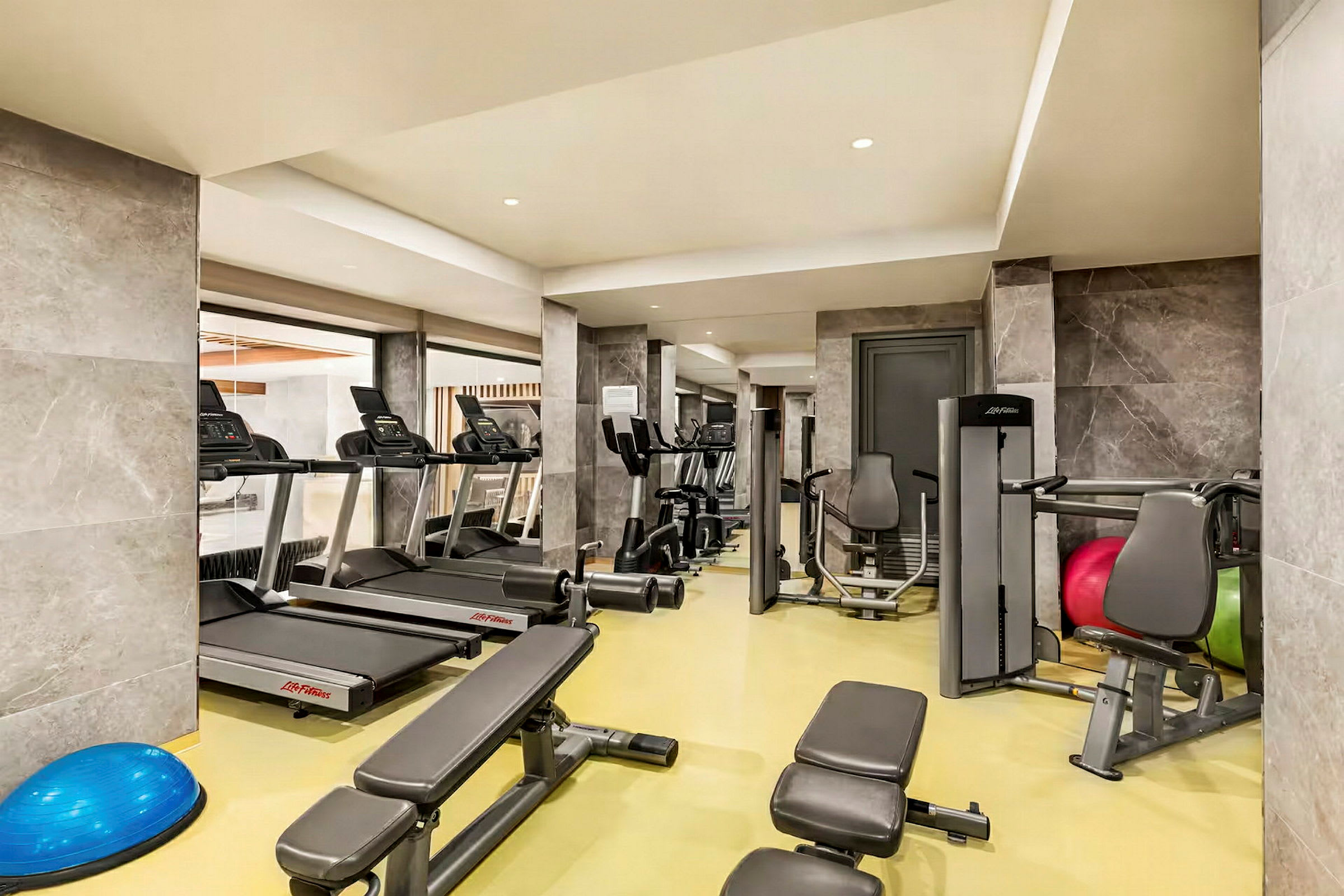 Bild av ett gym med träningsmaskiner och utrustning, inklusive löpband och styrketräningsbänkar. (AI-genererad text)