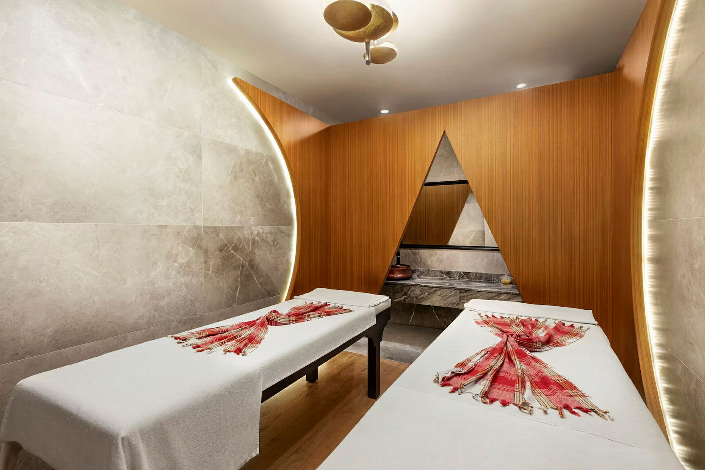 Två massagebänkar i ett modernt spa-rum med träpaneler och dekorativa element. (AI-genererad text)