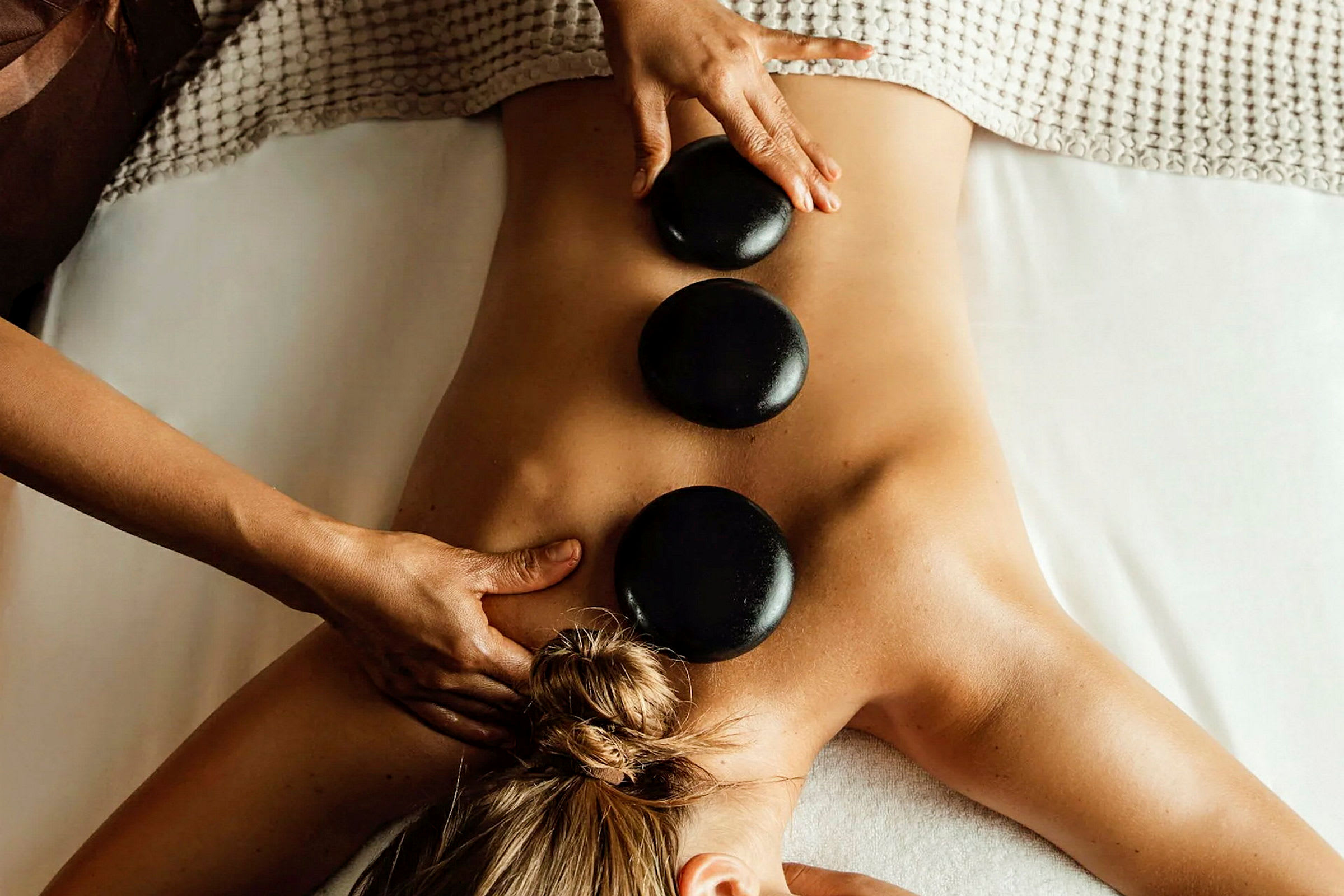 En person får en ryggmassage med varma stenar placerade på ryggen. (AI-genererad text)