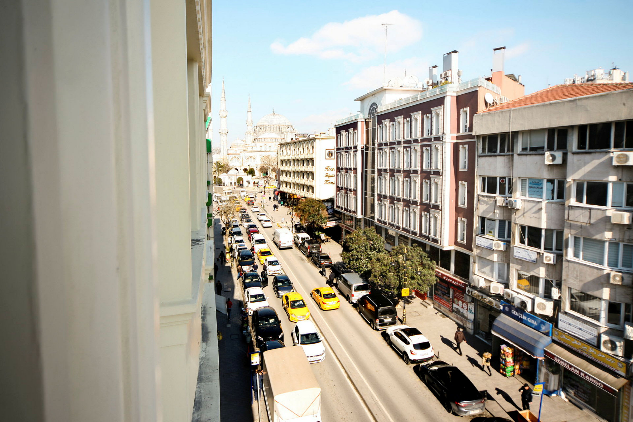 Bild av en stadsgata med trafik, byggnader längs vägen och en moské i bakgrunden. (AI-genererad text)