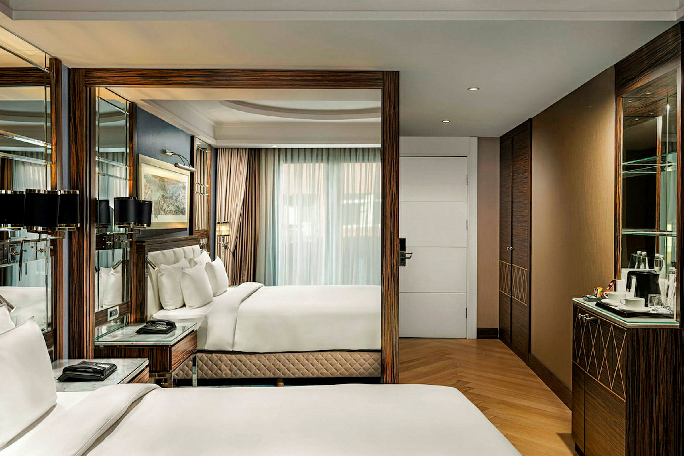 Ett elegant och modernt hotellrum med bekväma sängar och inredning i trä, en spegelvägg och stort fönster med gardiner. (AI-genererad text)