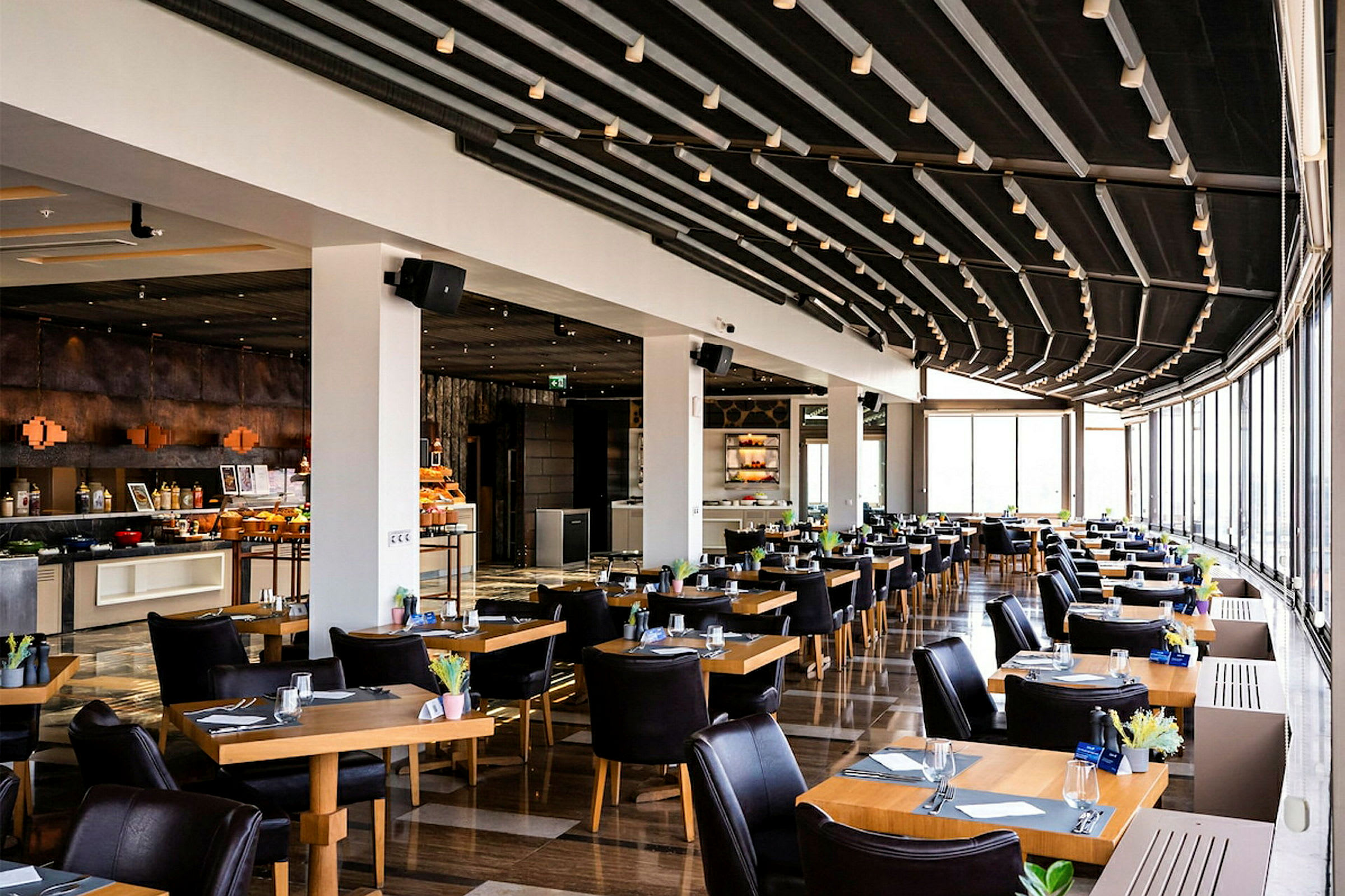 Restaurang med modernt inredda bord och stolar, stor glasyta som släpper in ljus. (AI-genererad text)