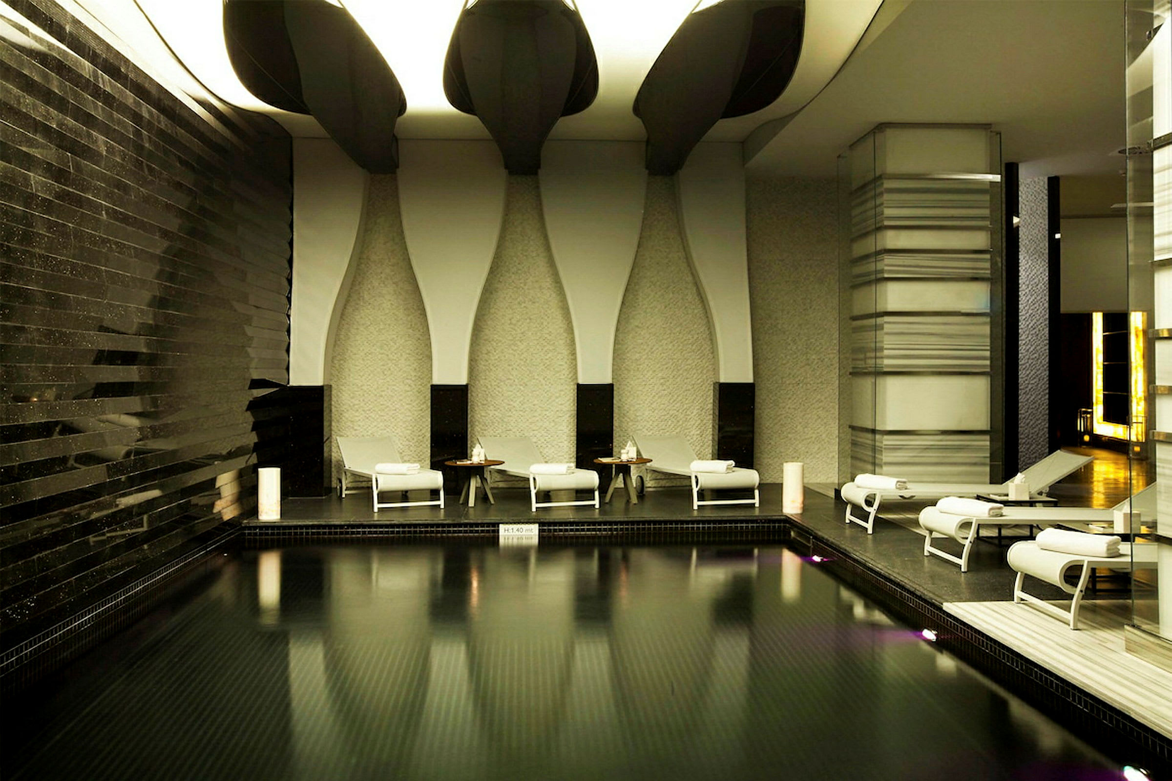 En inomhuspool med solstolar i en elegant miljö. (AI-genererad text)