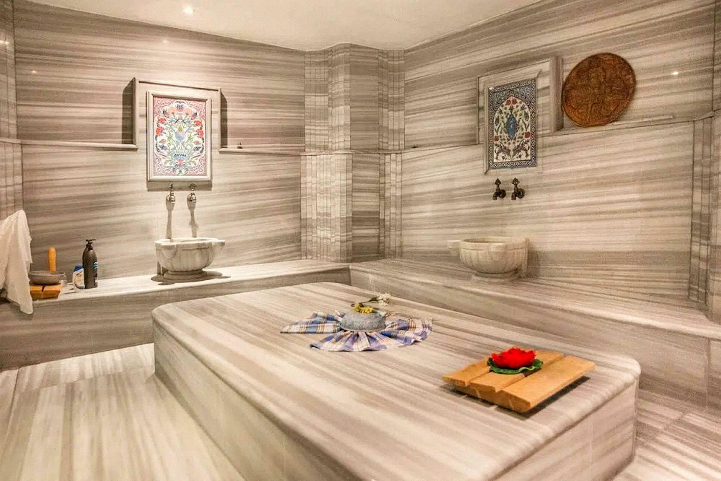 Ett traditionellt hamam med marmorinredning och dekorativa element samt en central plats för tvagning. (AI-genererad text)